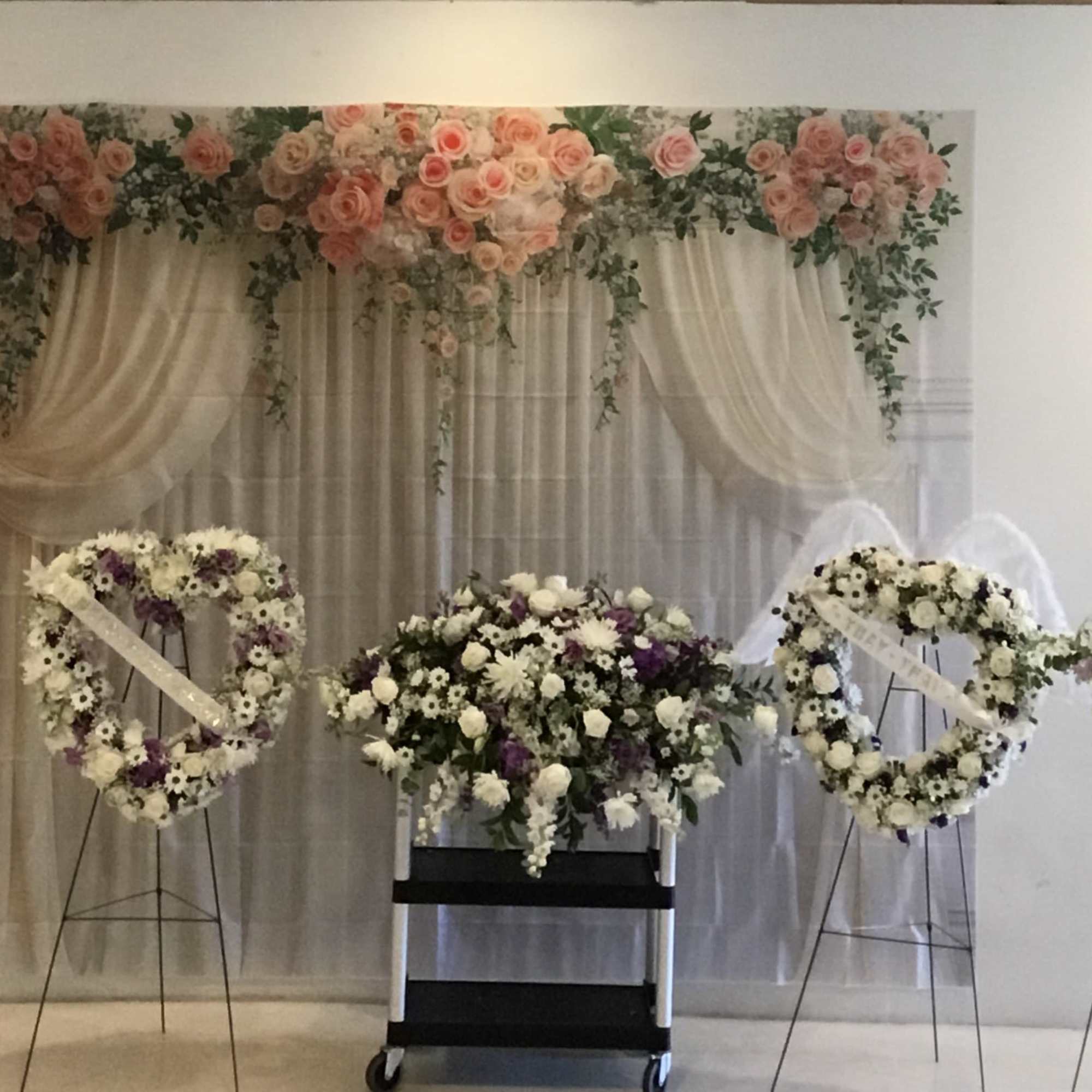 Wedding floral display with pink and white roses and white draped fabric