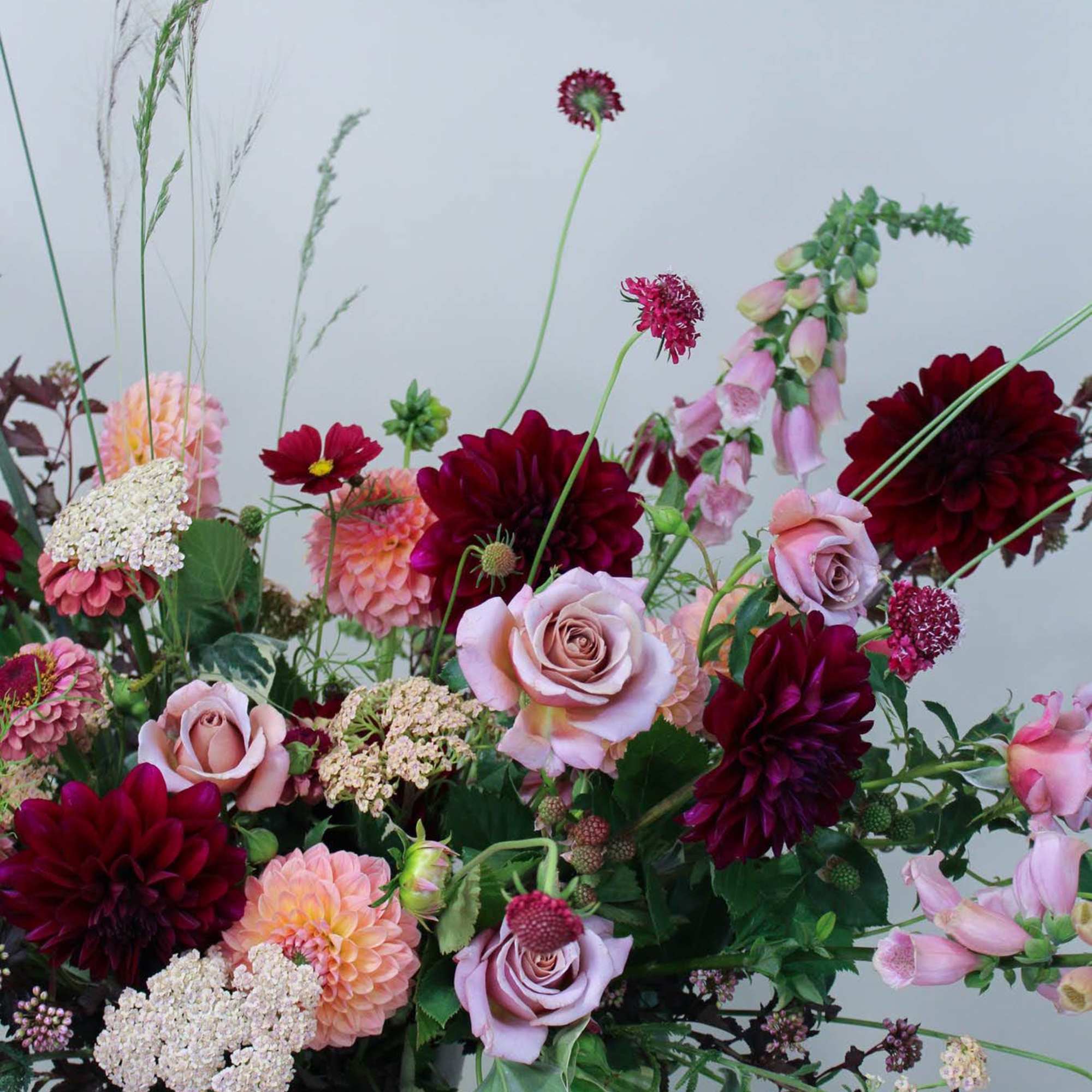 Mixed bouquet of pink and burgundy flowers in a dark vase