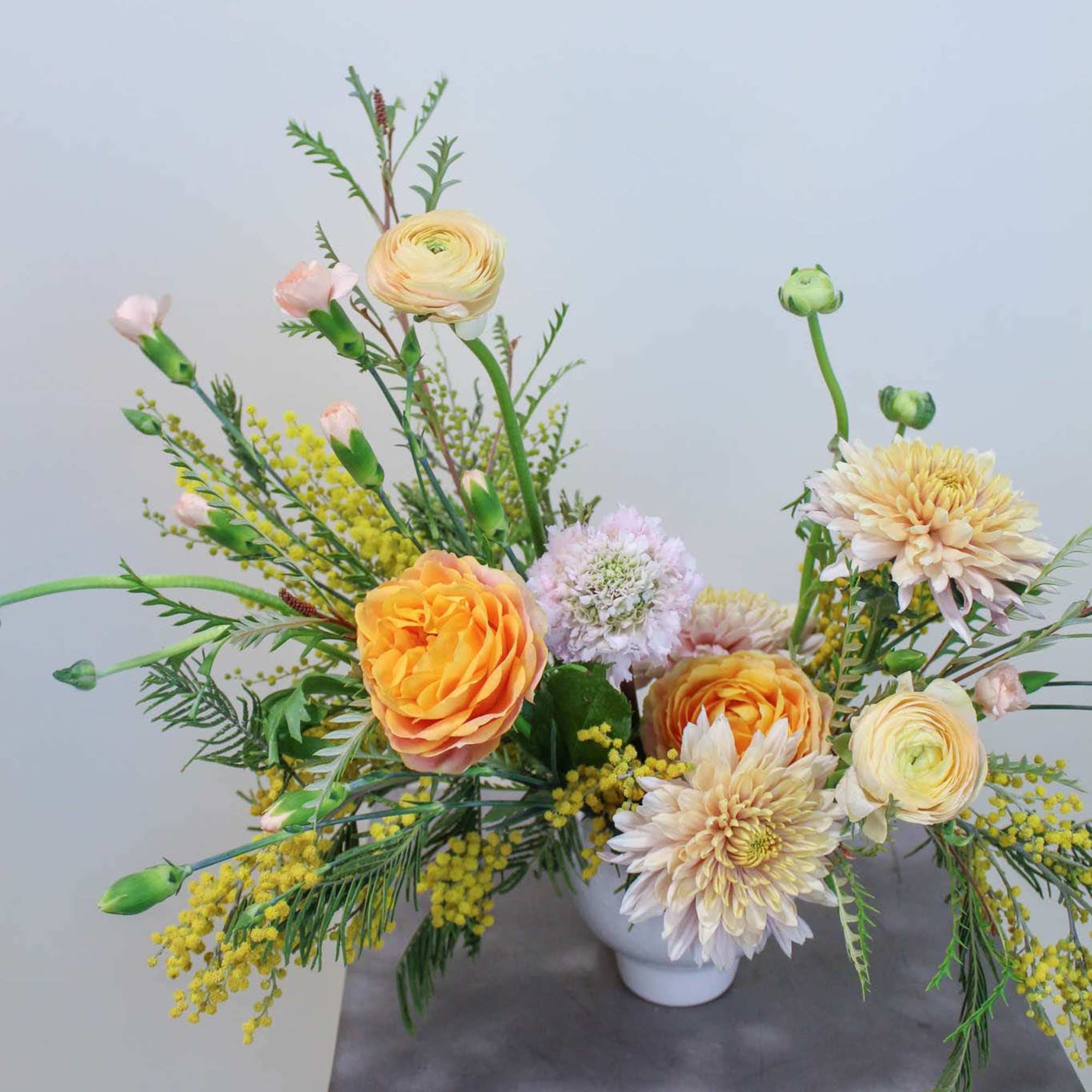 Mixed pastel floral arrangement in a white vase