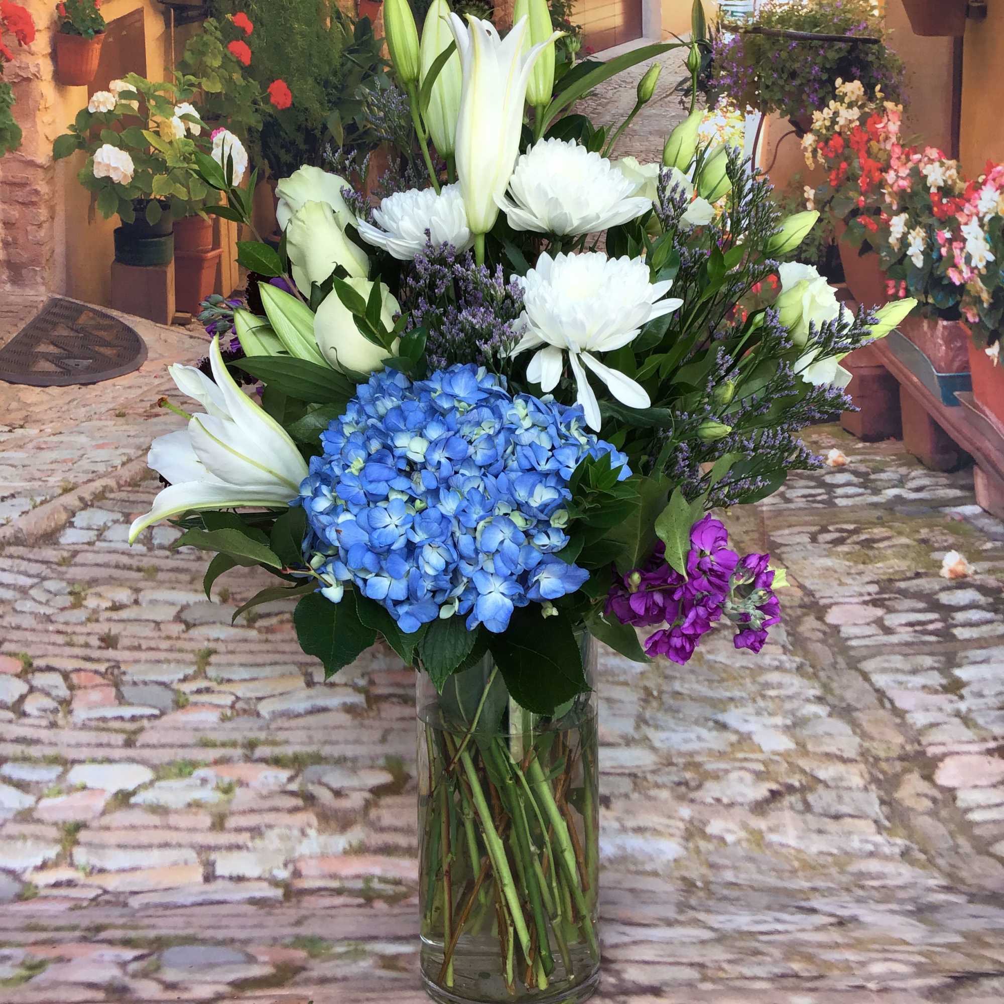 Blue hydrangea and white lily bouquet in a clear glass vase