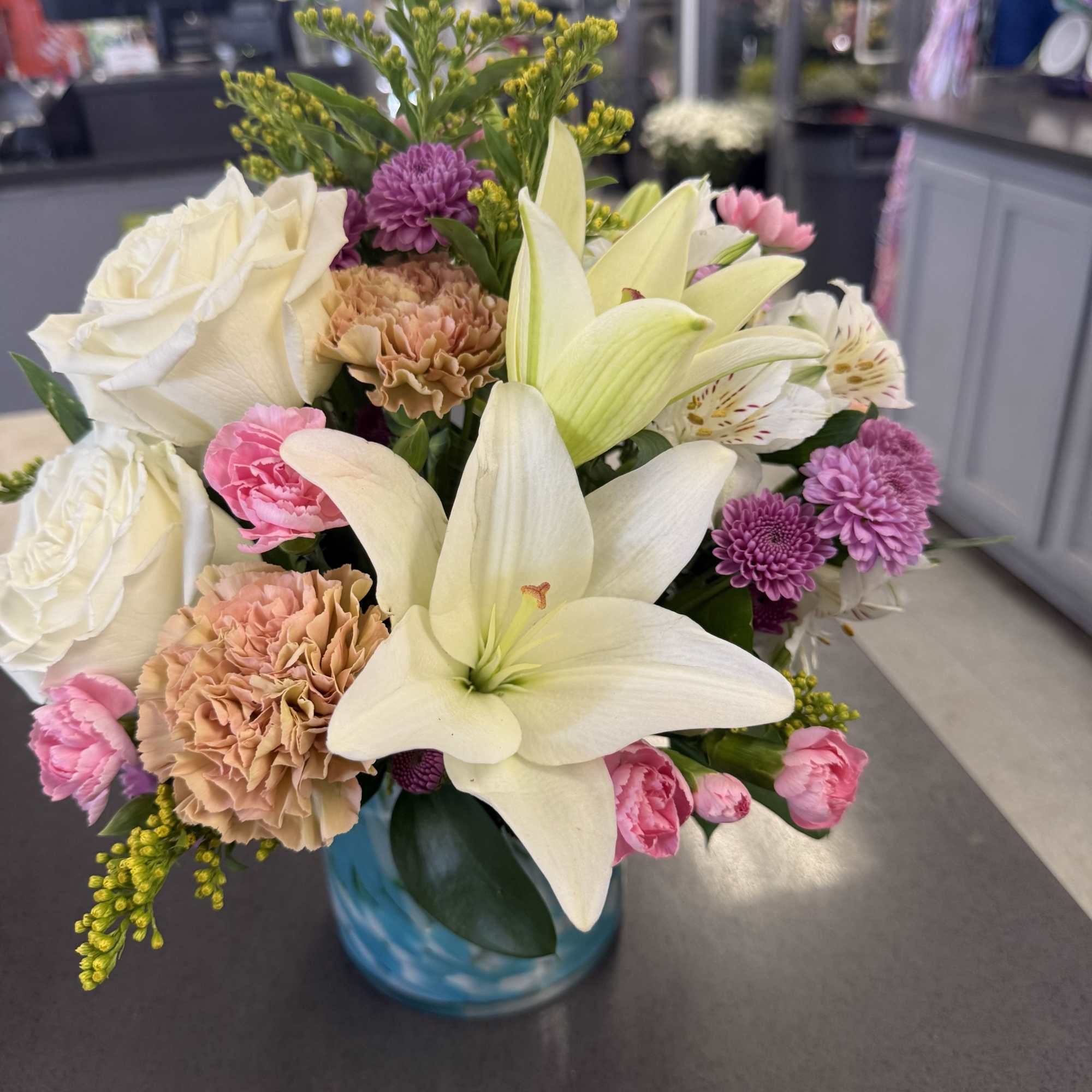 Soft pastels meet a modern blue glass vase in this charming flower