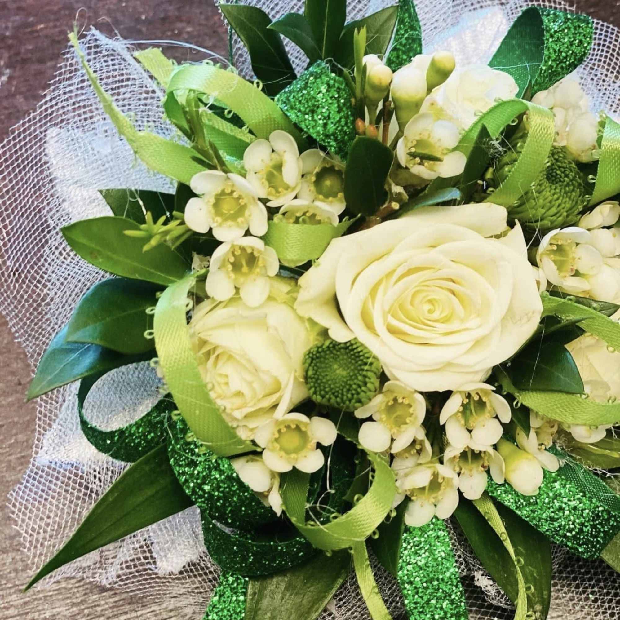 A timeless corsage featuring a pristine white rose nestled among fresh, lush, photo 3 of 5