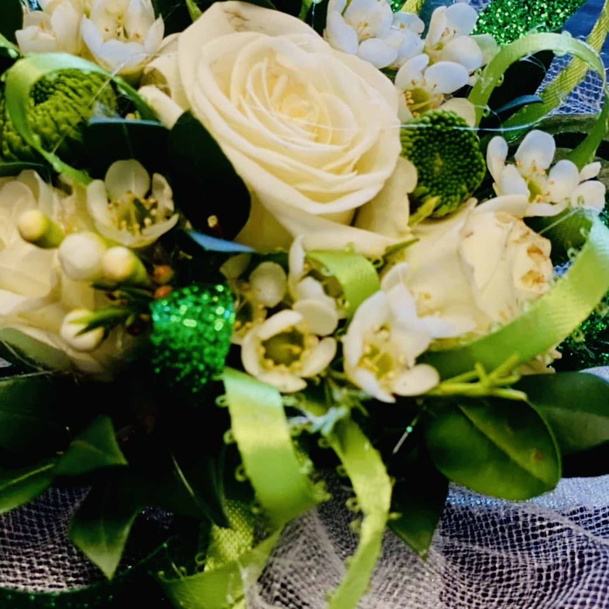 A timeless corsage featuring a pristine white rose nestled among fresh, lush, photo 5 of 5