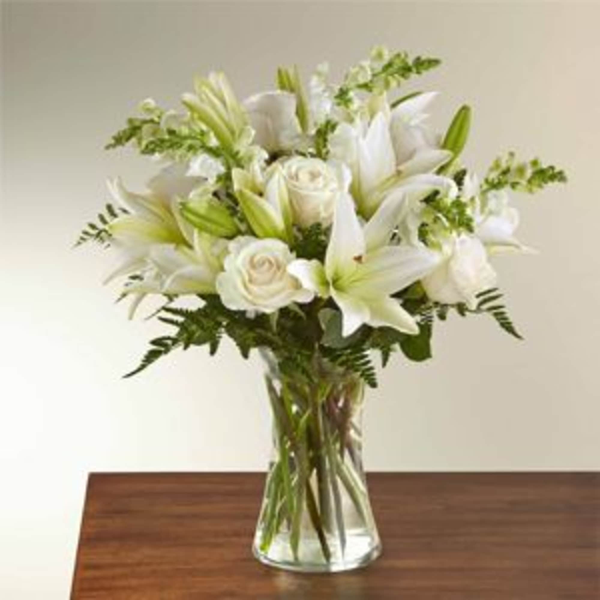 White lilies and roses in a clear glass vase