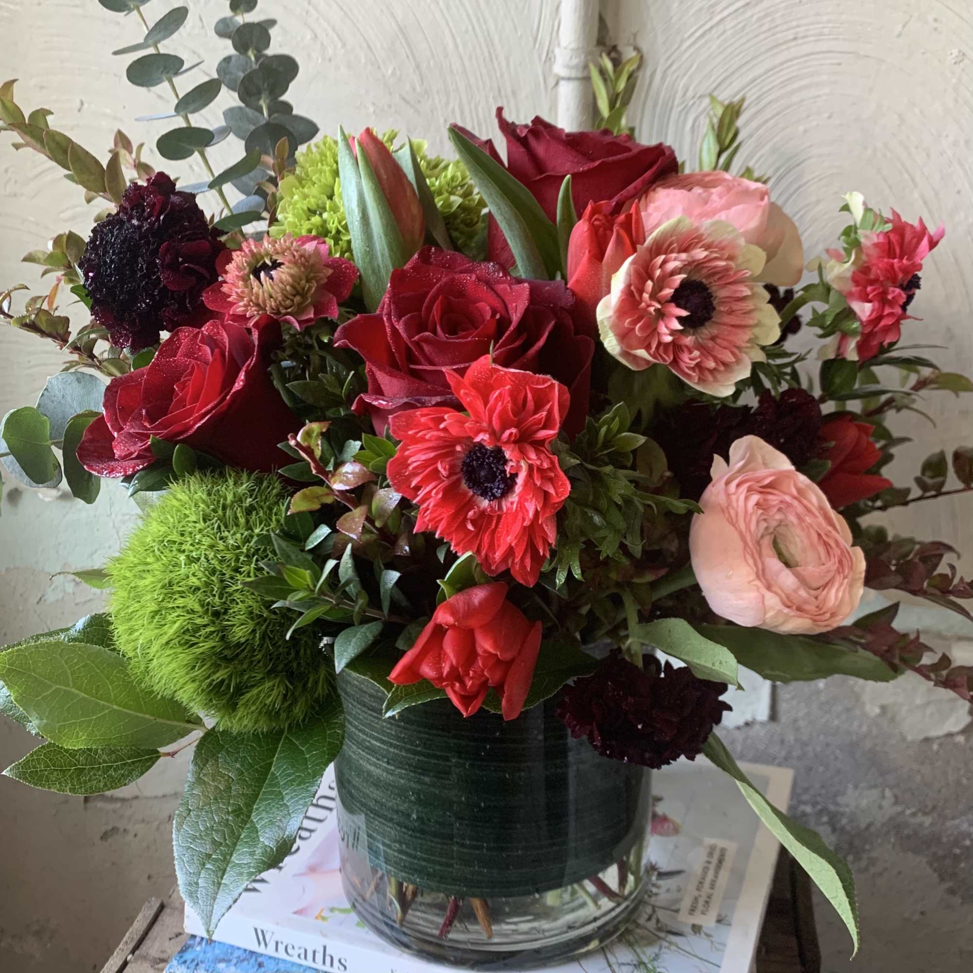 Red roses and pink blooms arranged in a glass vase