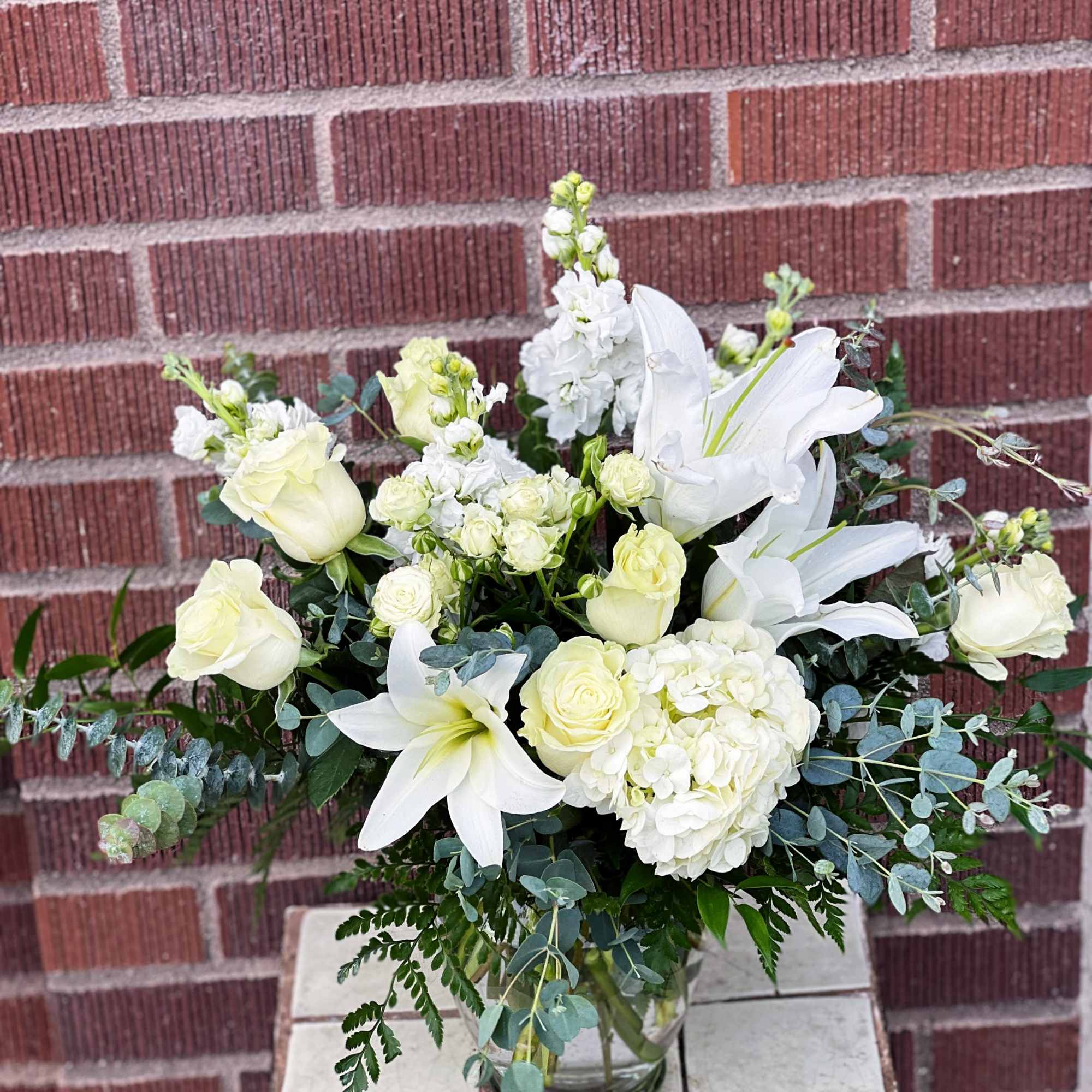 White roses and lilies arranged in a glass vase