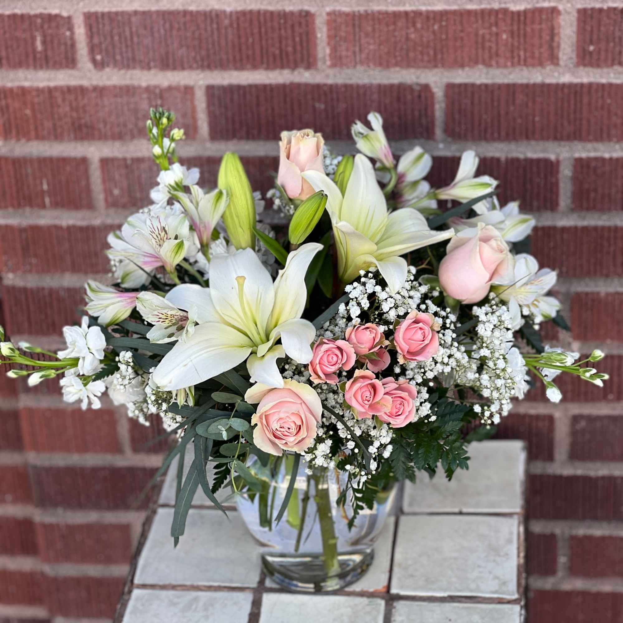 Pink roses and white lilies arranged in a clear glass vase