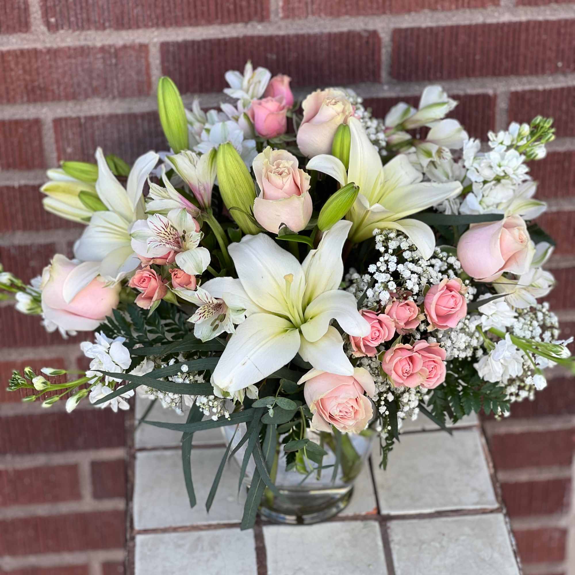 Pink roses and white lilies arranged in a glass vase