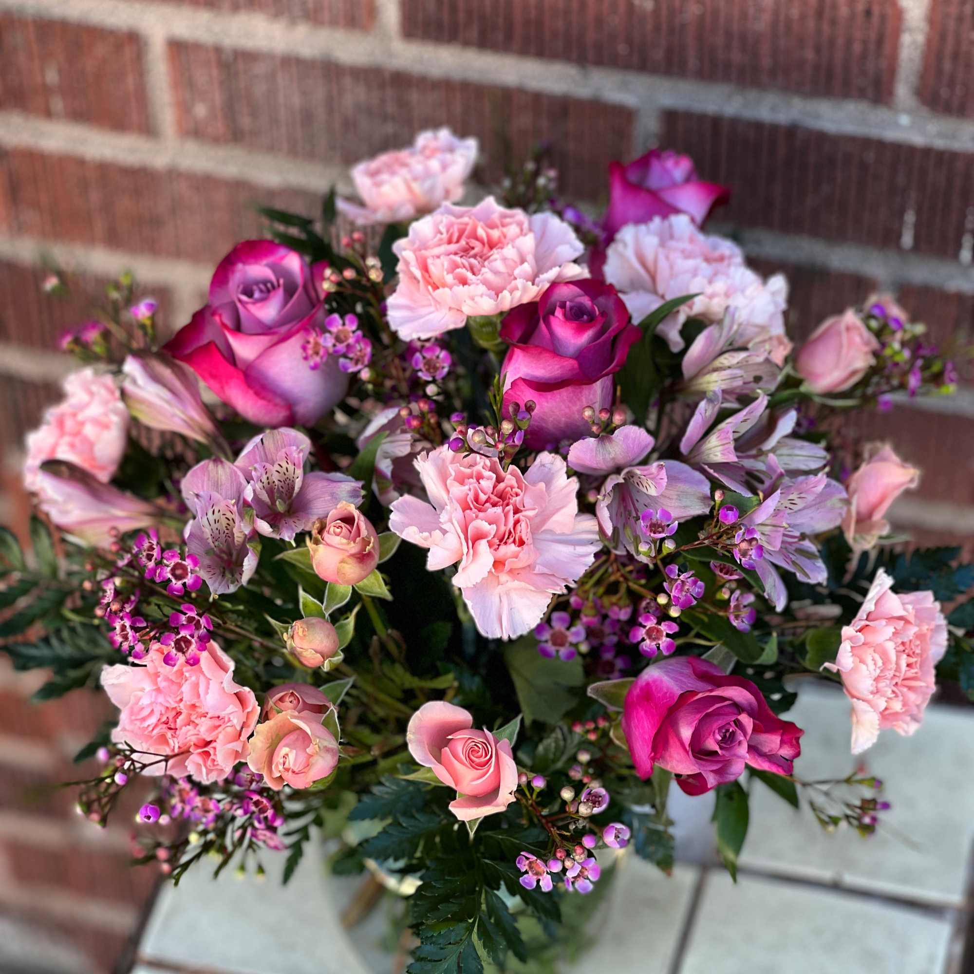 Bouquet of pink roses, carnations, and alstroemeria in a glass vase