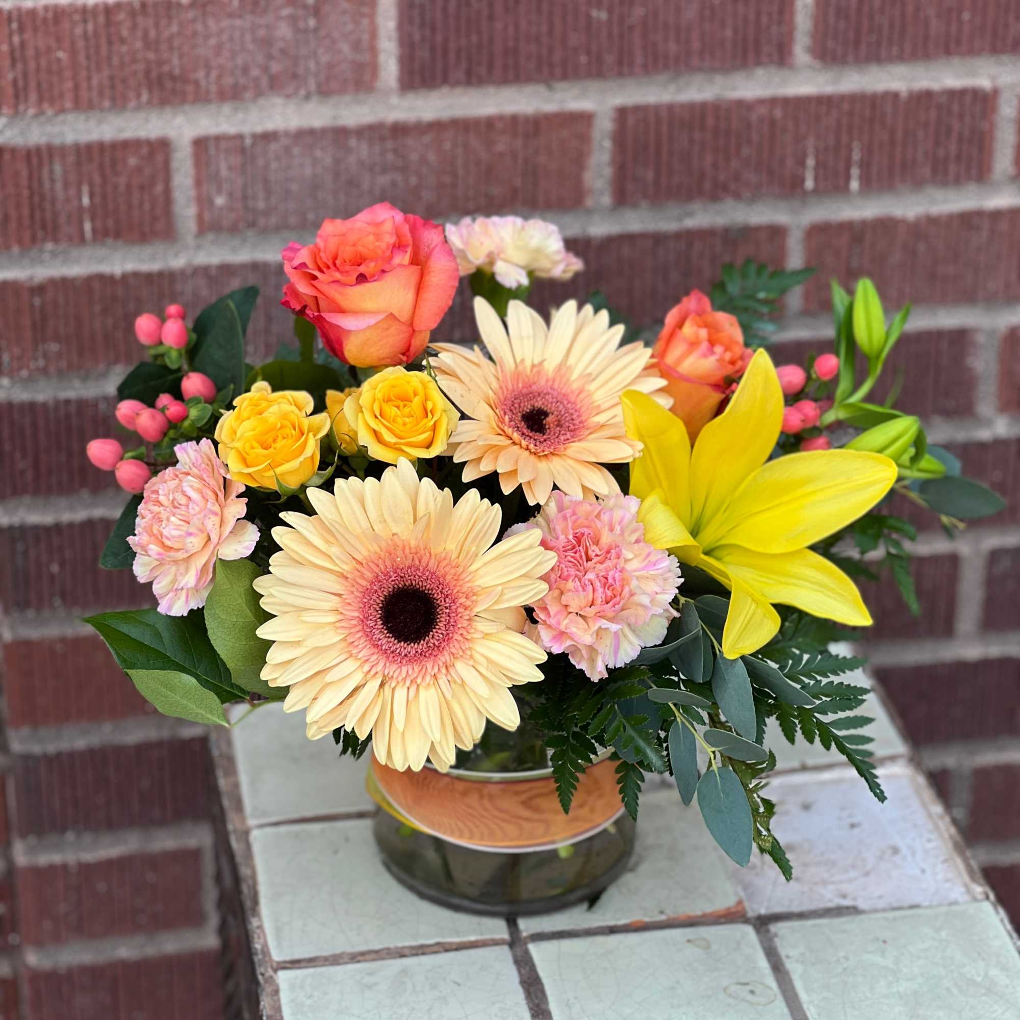 Mixed bouquet in a glass vase with roses, gerbera daisies, lilies, and carnations