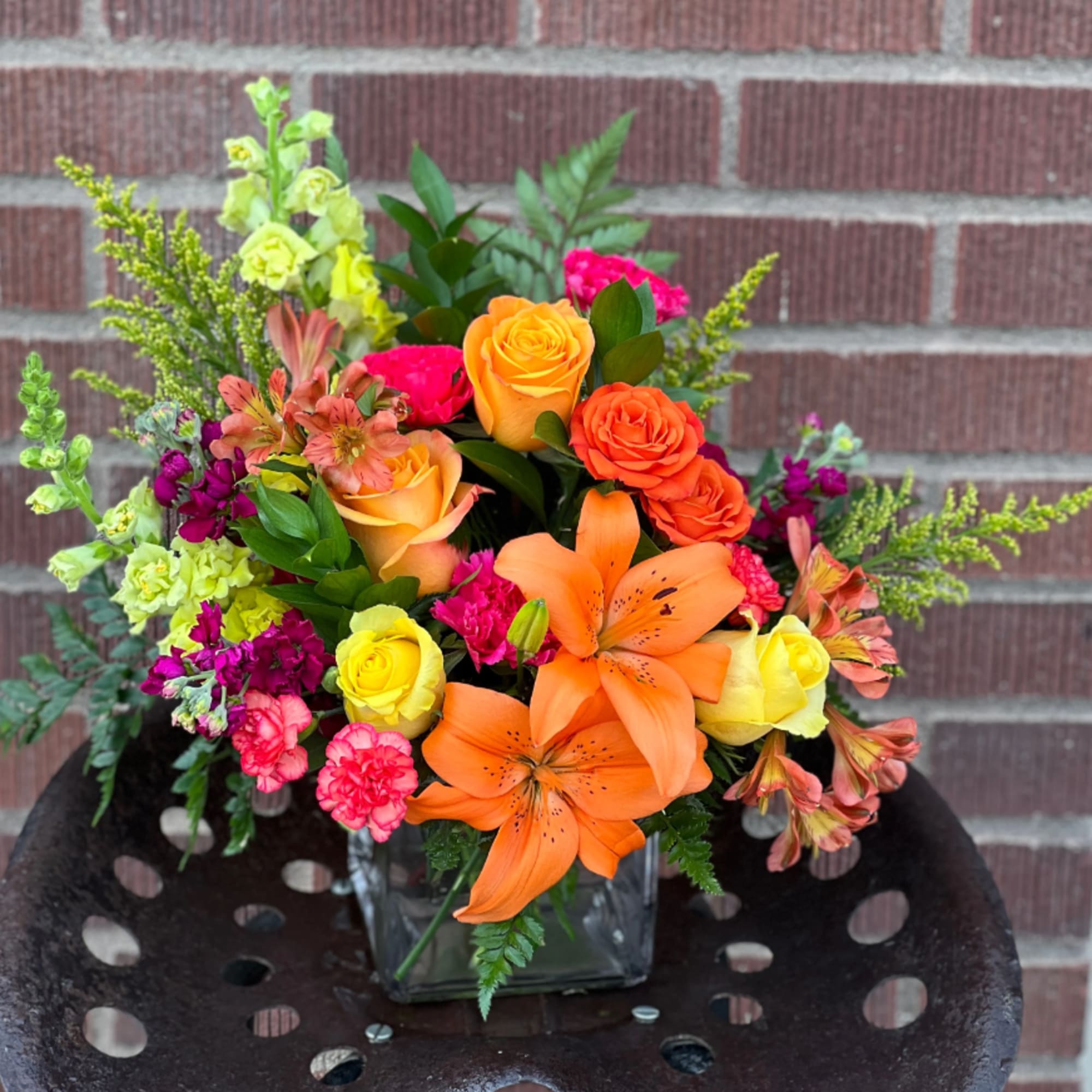 Bright mixed bouquet with orange lilies and roses in a glass vase
