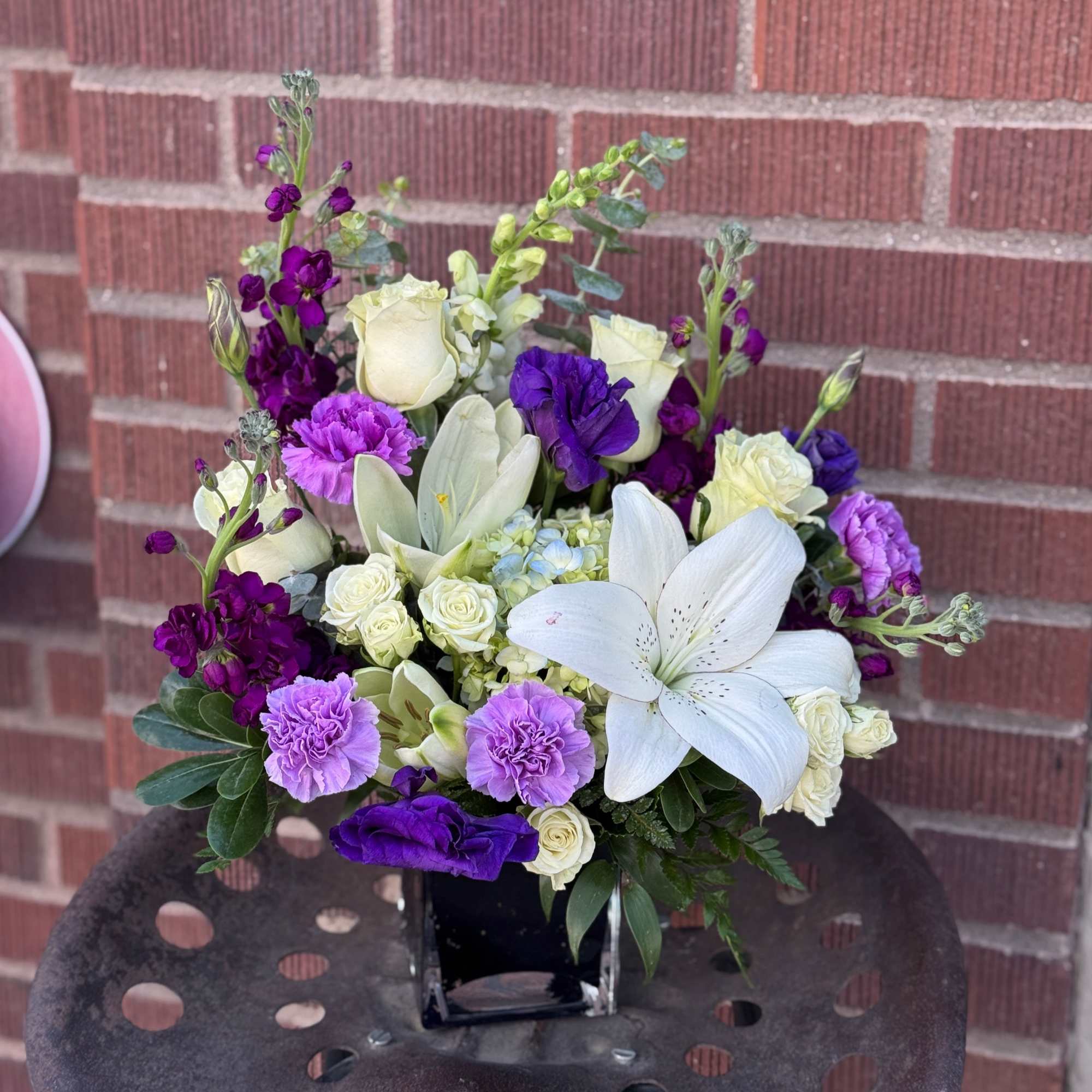 Purple and white floral arrangement in a black vase