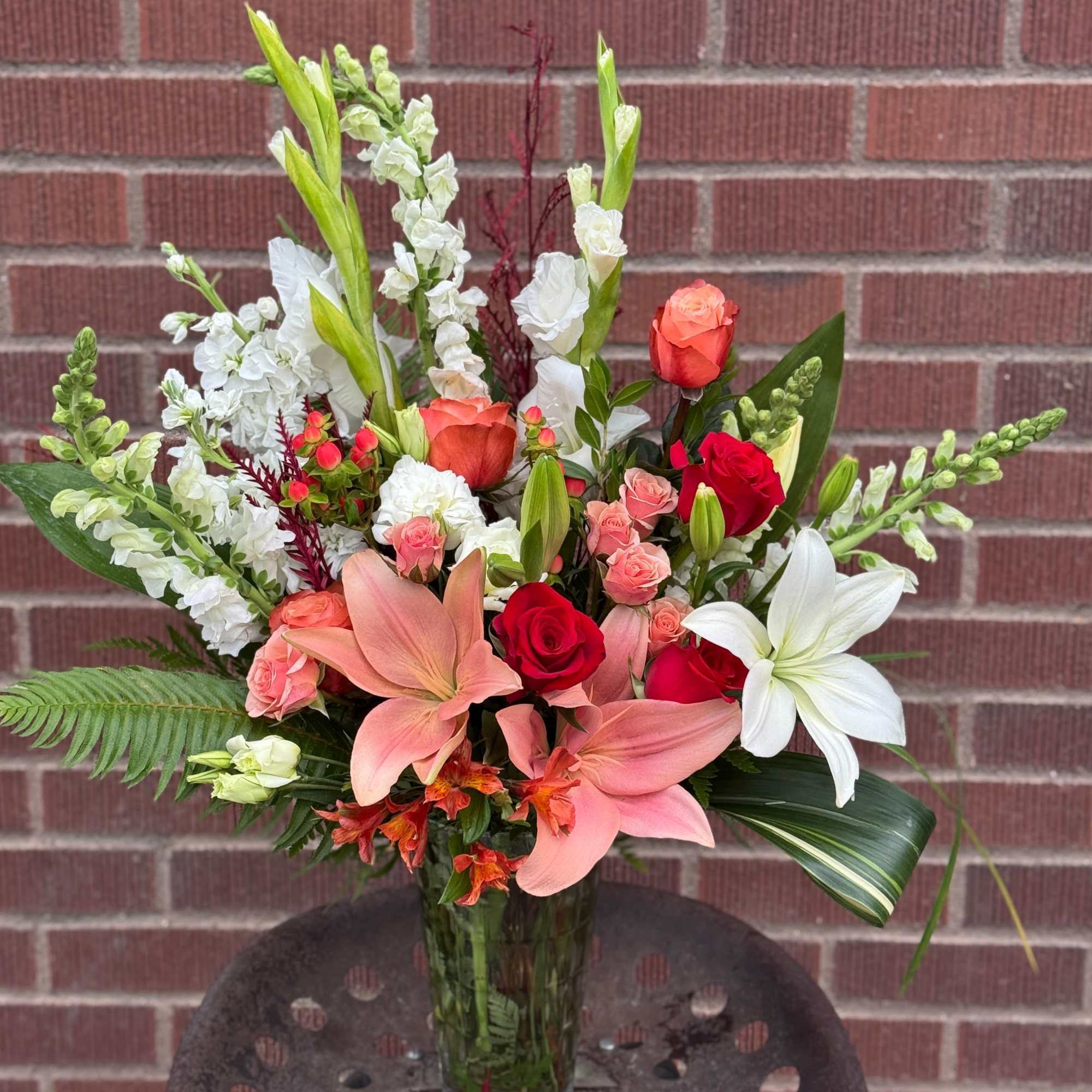 Mixed bouquet with lilies, roses, and white snapdragons in a glass vase