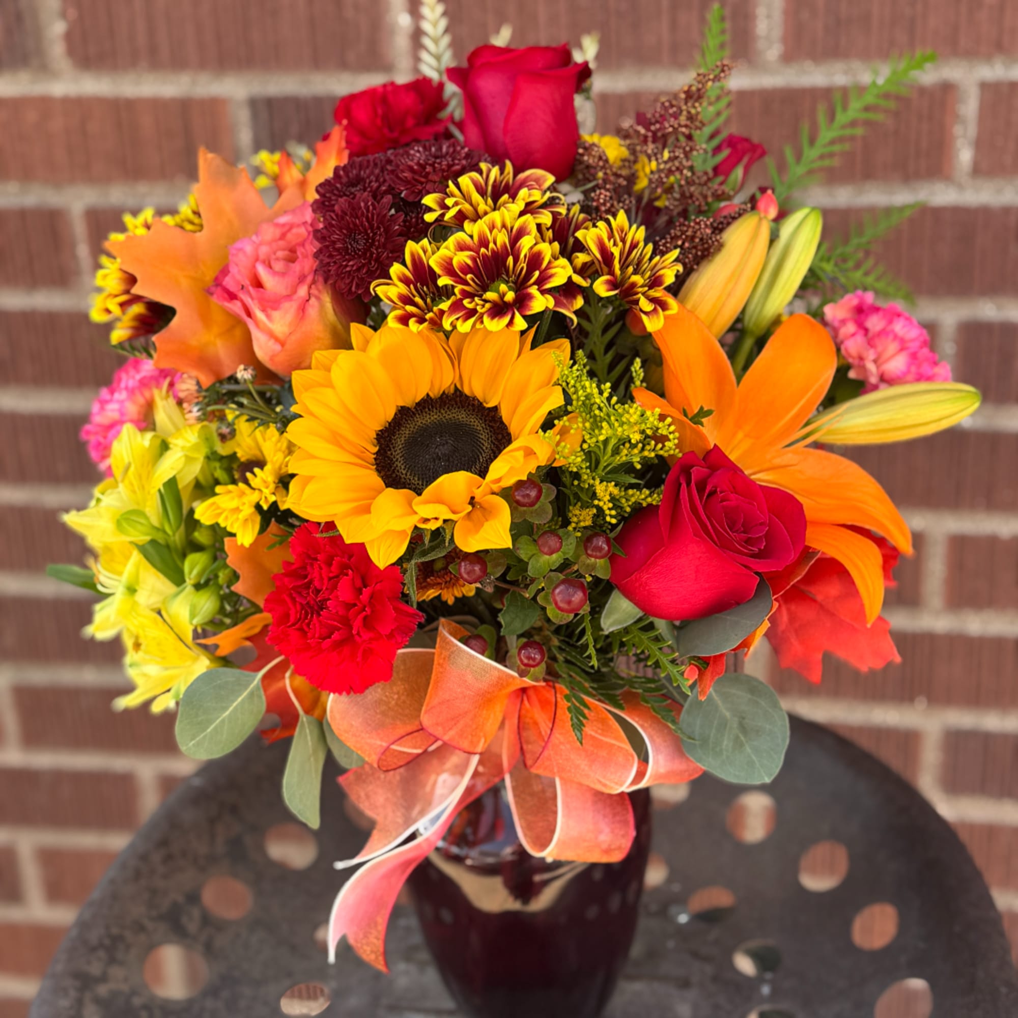 Colorful bouquet with sunflowers, roses, lilies, and chrysanthemums in a glass vase