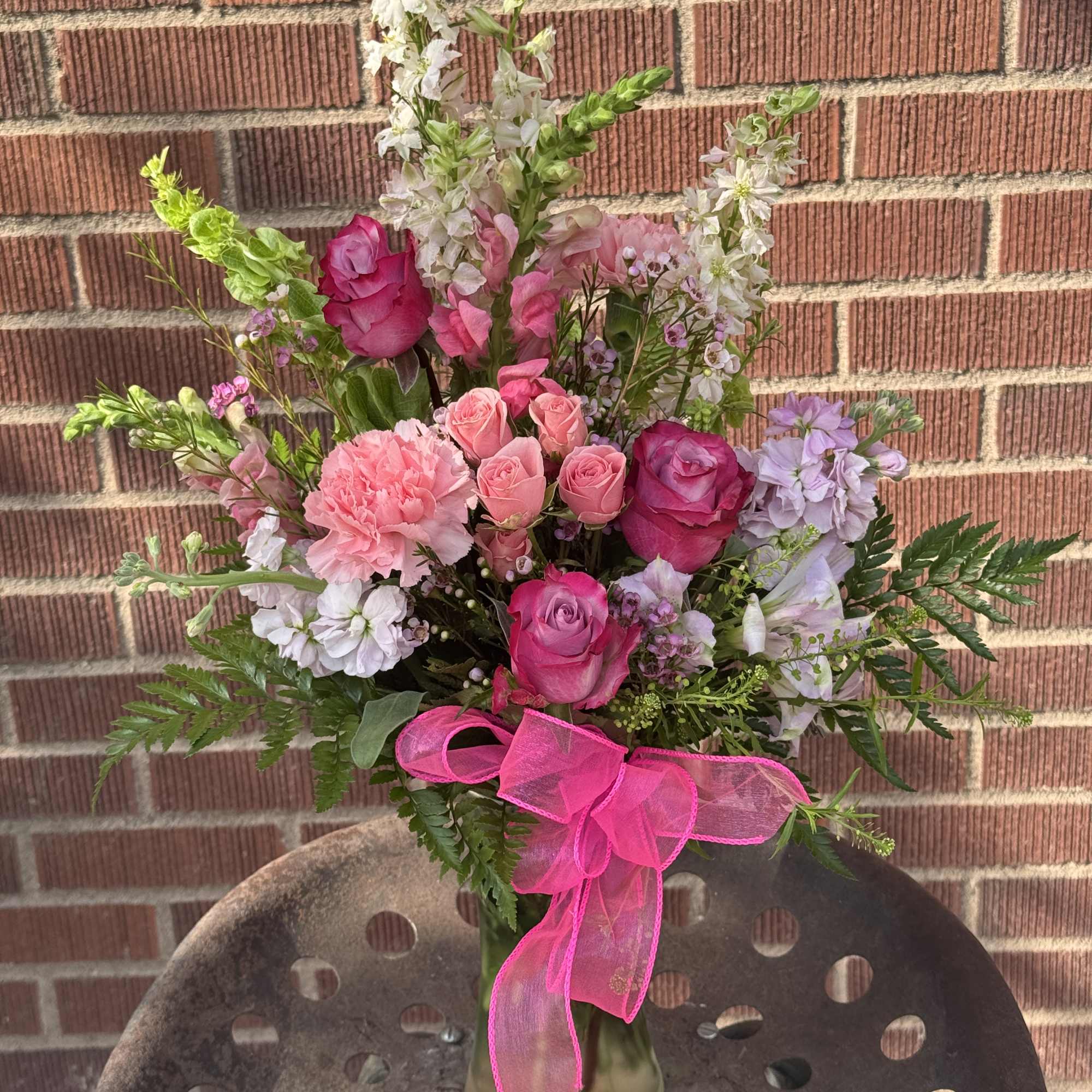 Pink and white mixed bouquet in a glass vase with a bright ribbon