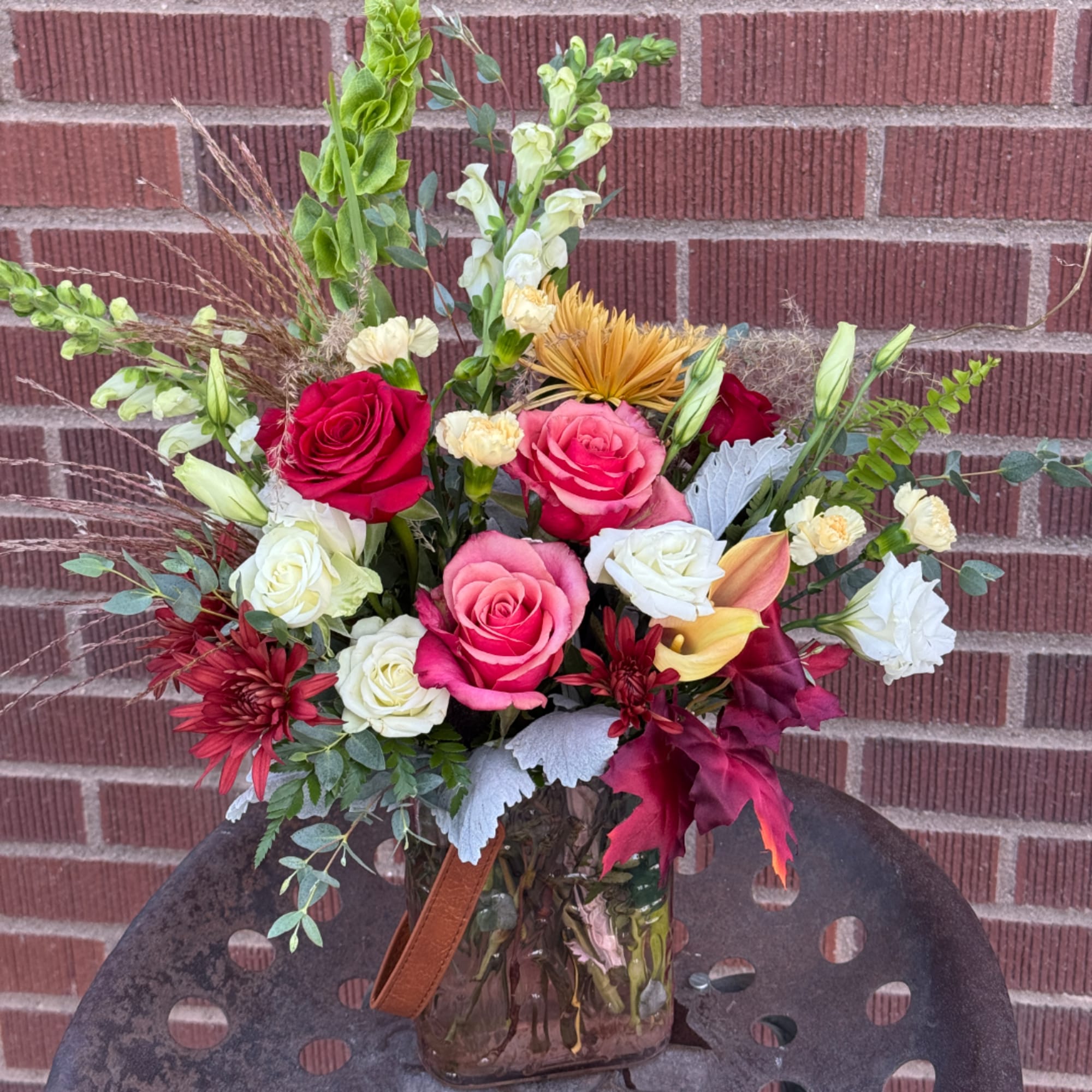 Mixed bouquet of roses, snapdragons, and calla lilies in a glass vase