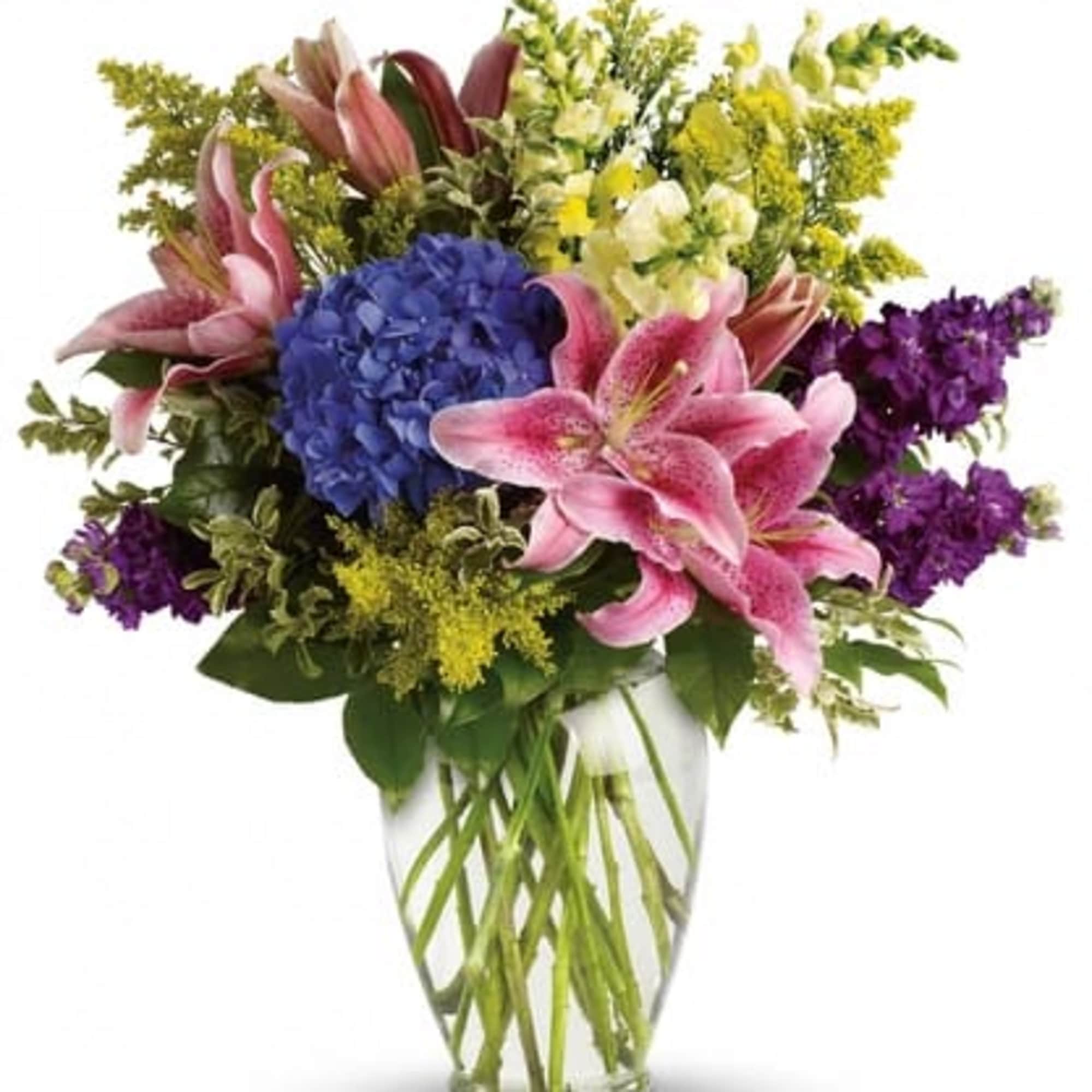 Mixed bouquet of pink lilies, blue hydrangea, and purple and yellow blooms in a clear glass vase