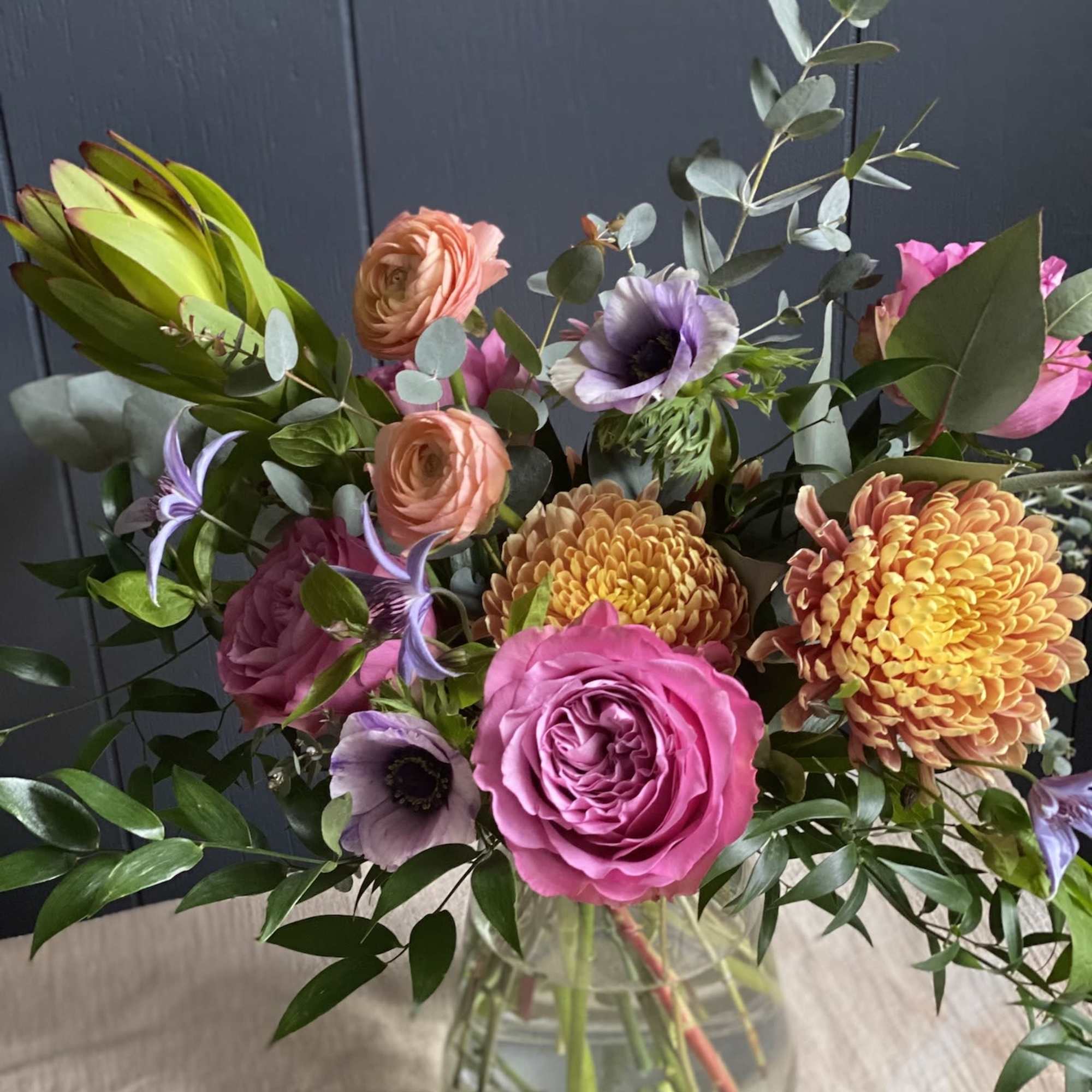 Mixed bouquet of pink, peach, and purple flowers in a glass vase