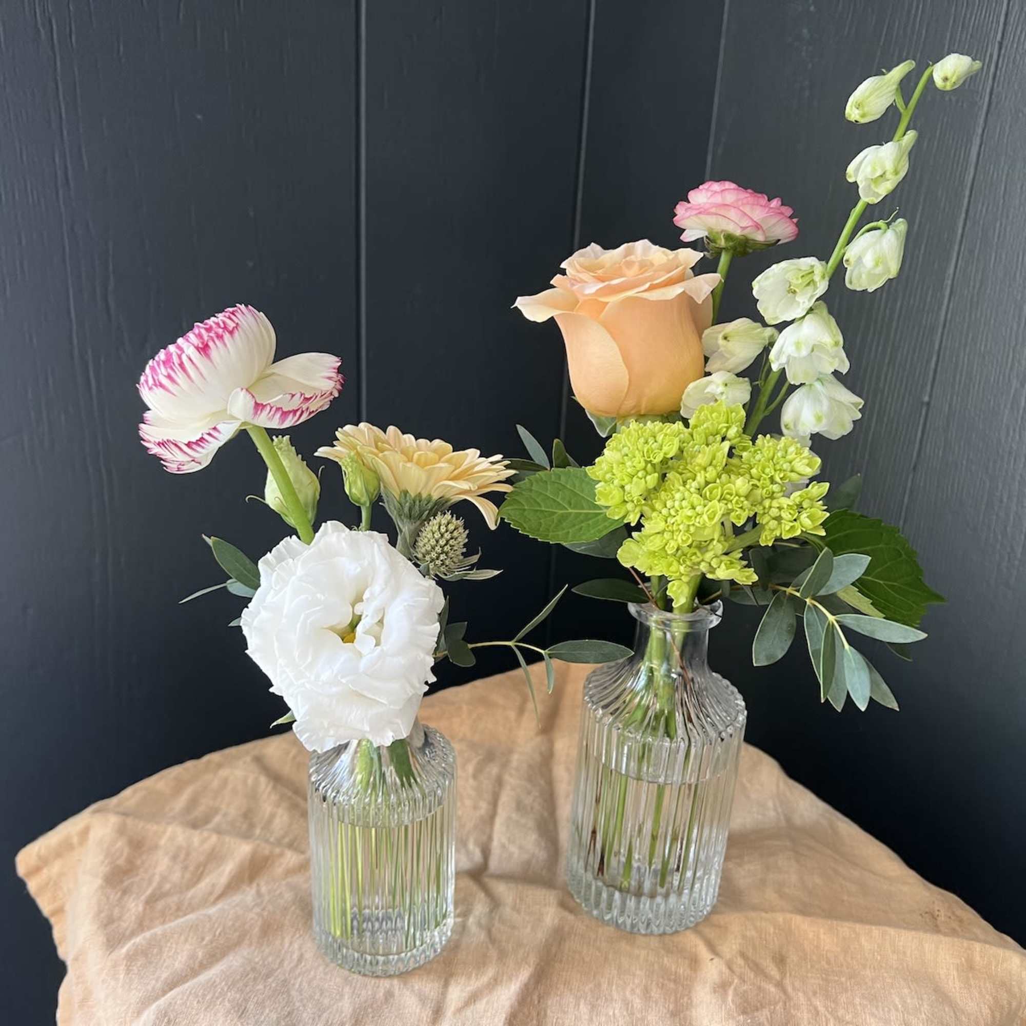 Two small floral arrangements in ribbed glass vases with roses and mixed blooms