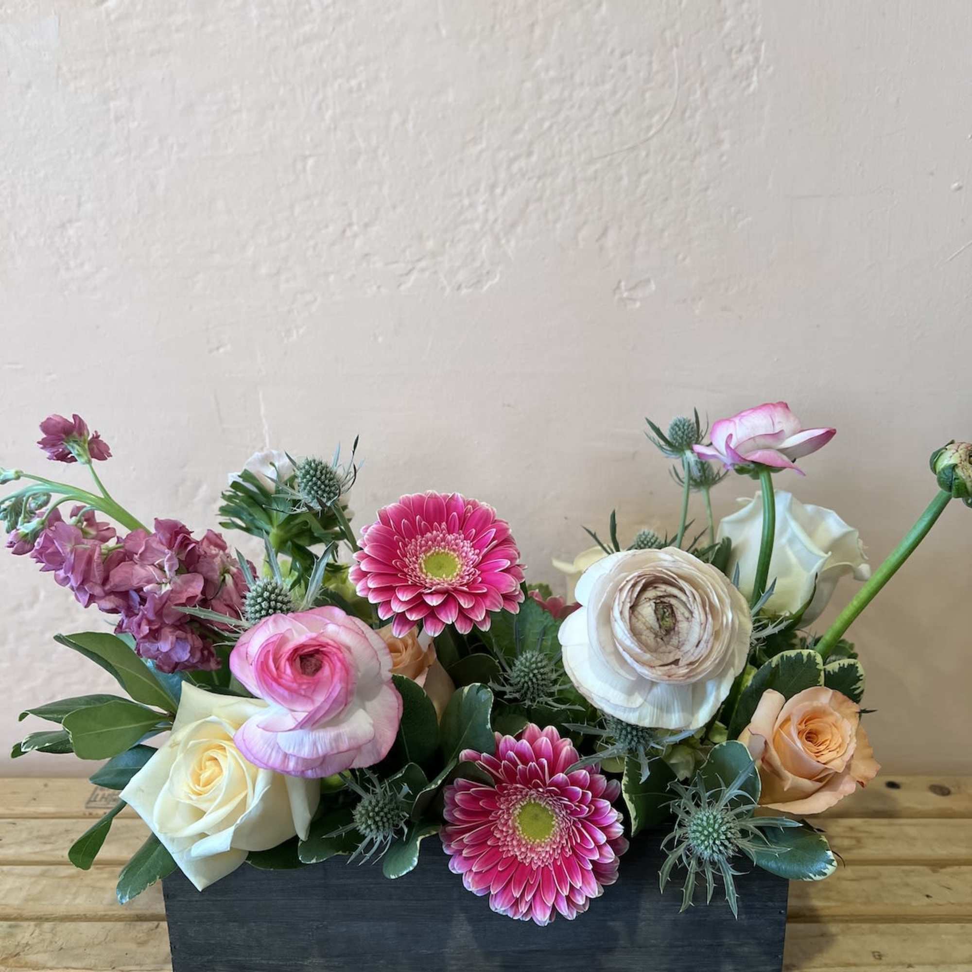Mixed bouquet with pink gerbera daisies, roses, and ranunculus in a black box