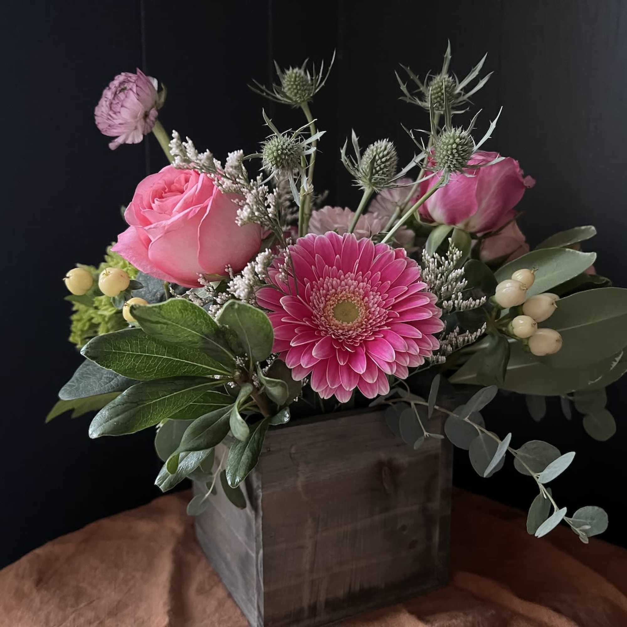 Pink roses and a gerbera daisy in a wooden box arrangement