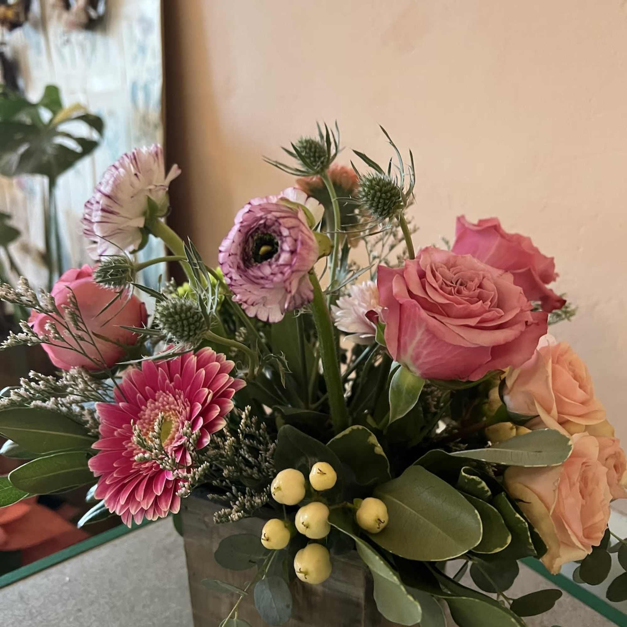 Pink and peach roses with mixed blooms in a square glass vase