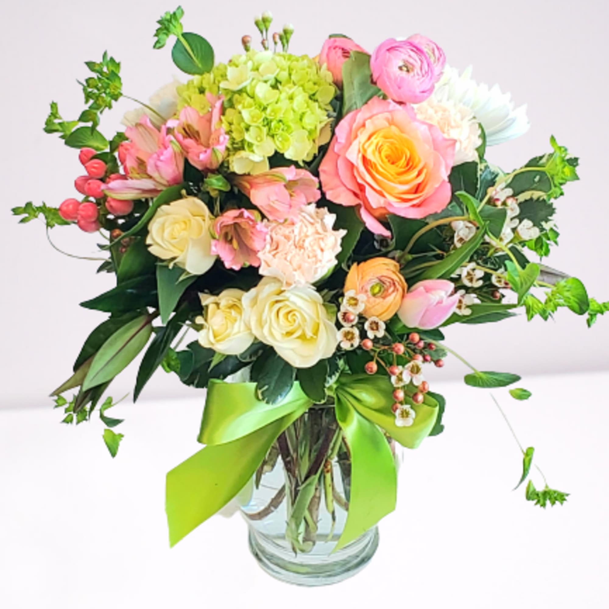 Mixed bouquet of pink, yellow, and white flowers in a glass vase