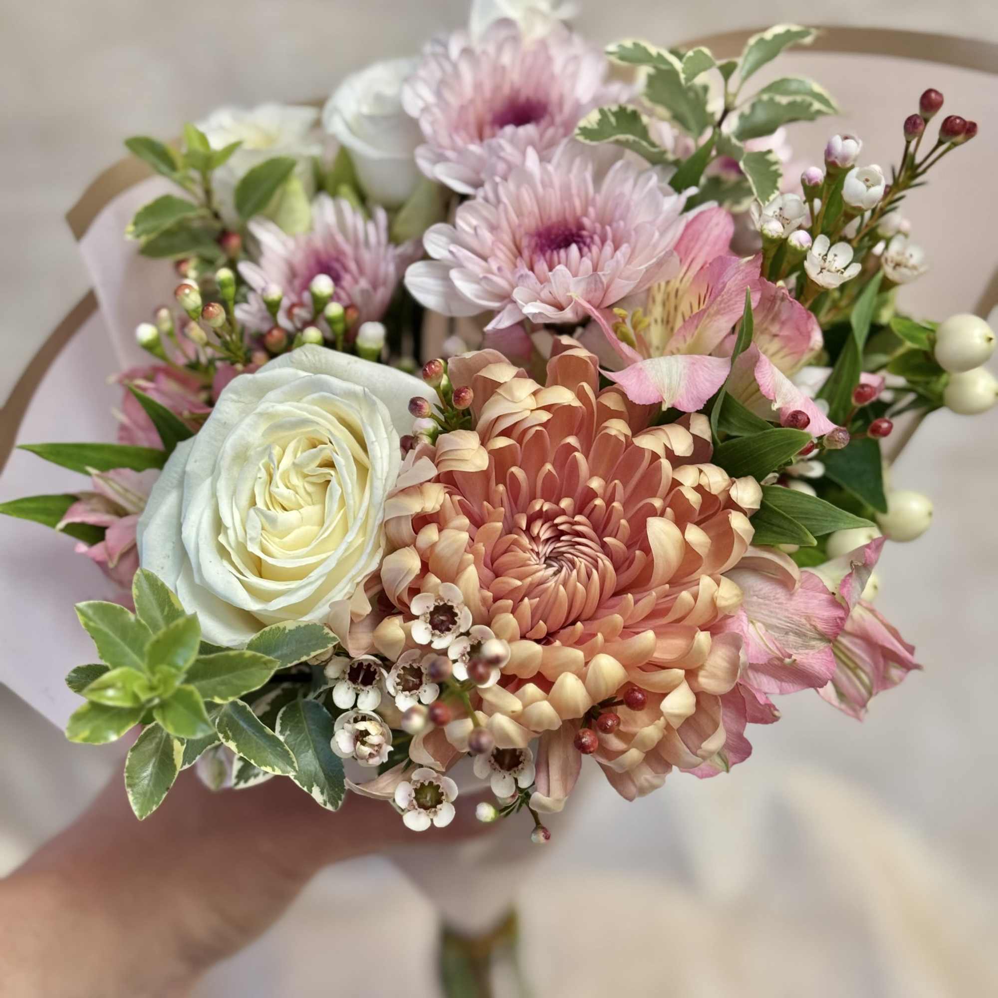 Handheld bouquet of pink and peach flowers with a white rose