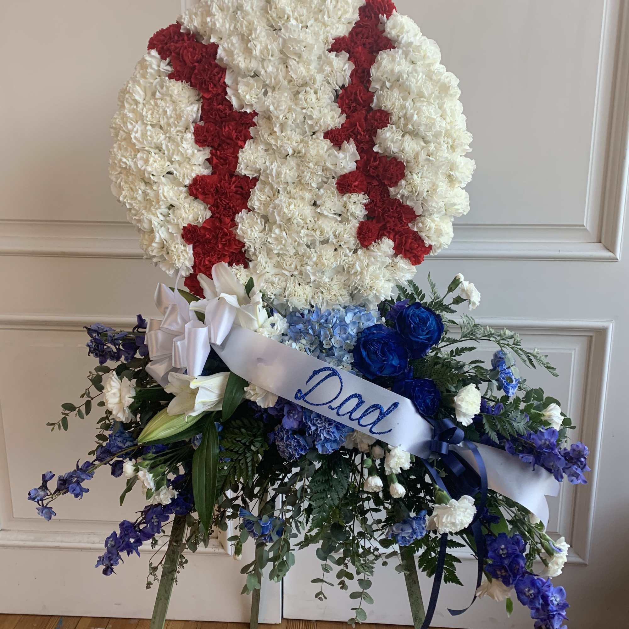 Standing funeral spray with white and red carnations and blue flowers