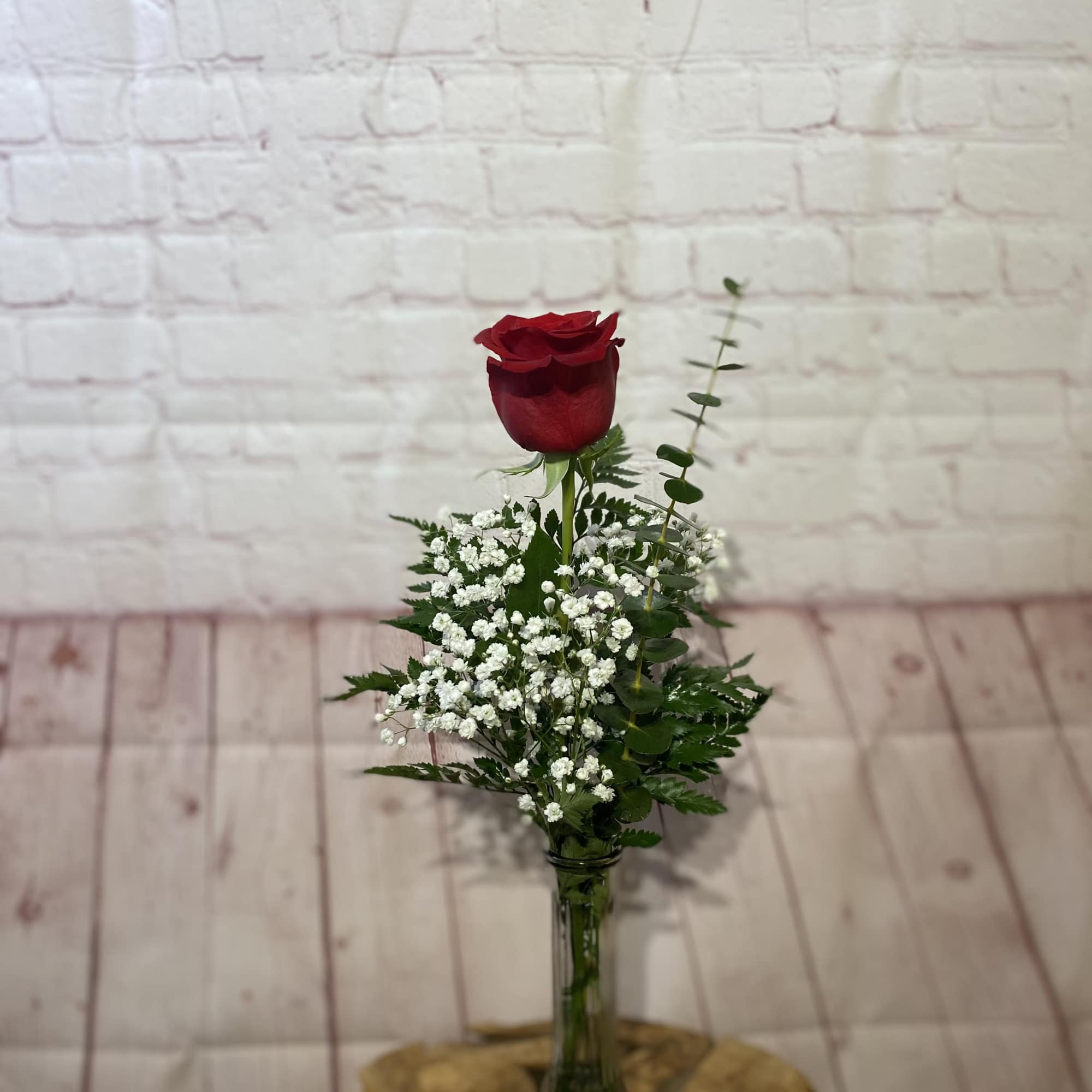 Single red rose in a glass vase with white baby's breath