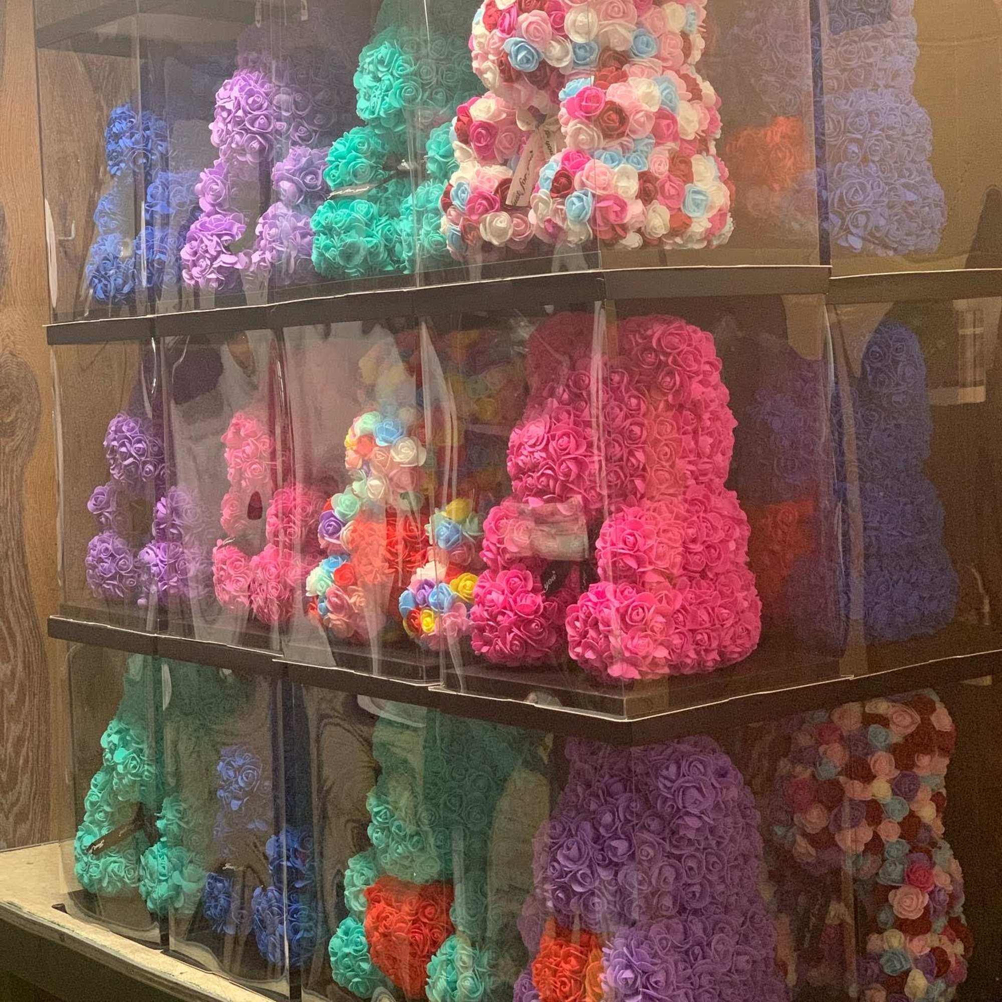 Shelves of colorful rose-shaped teddy bears in clear boxes