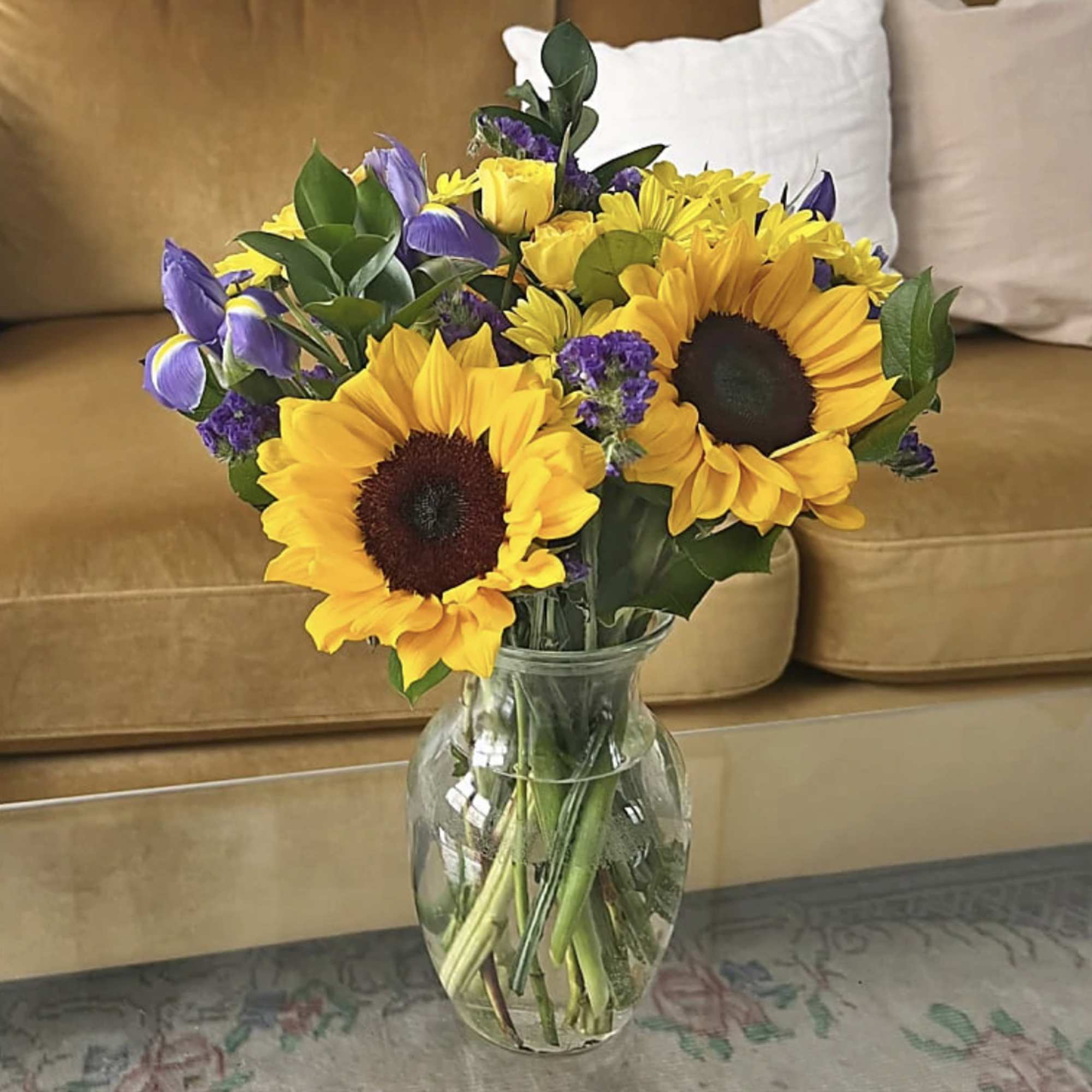 Sunflowers and purple flowers arranged in a clear glass vase