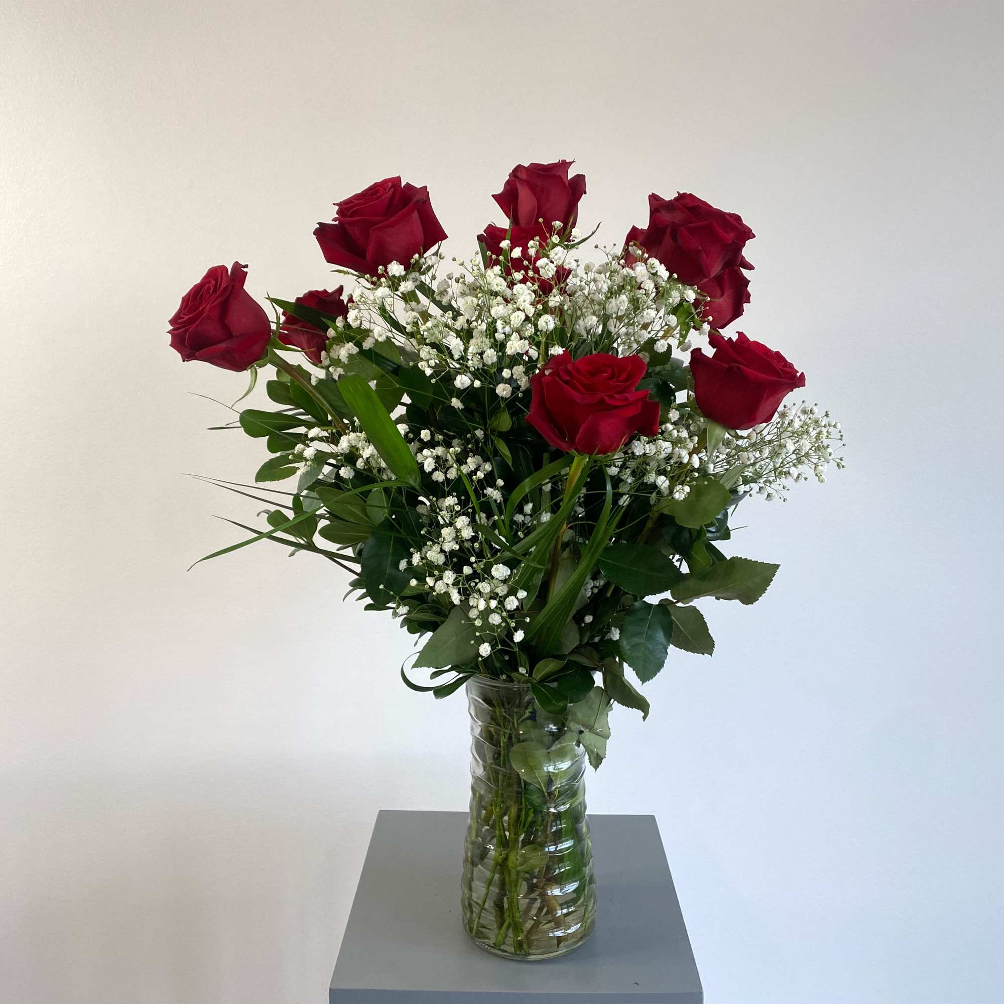 Red roses in a clear glass vase with baby's breath
