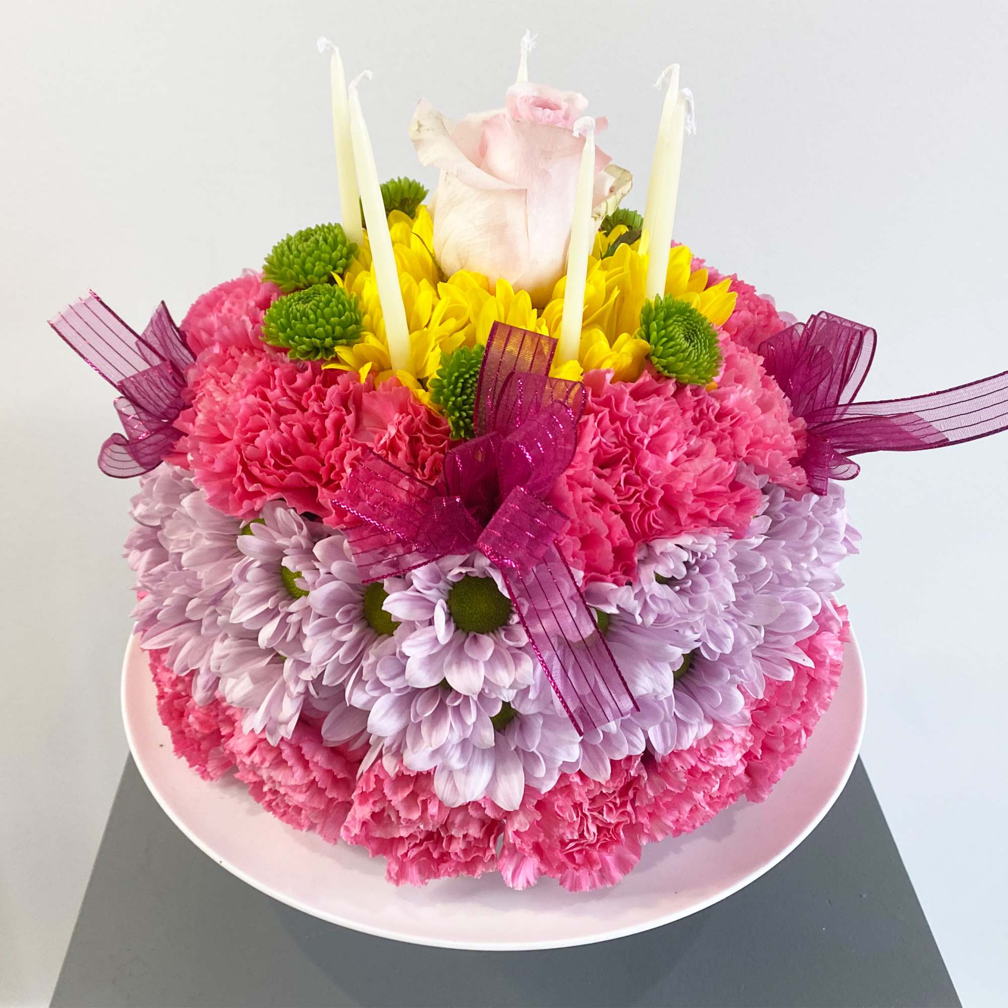 Pink and lavender floral arrangement with candles on a plate