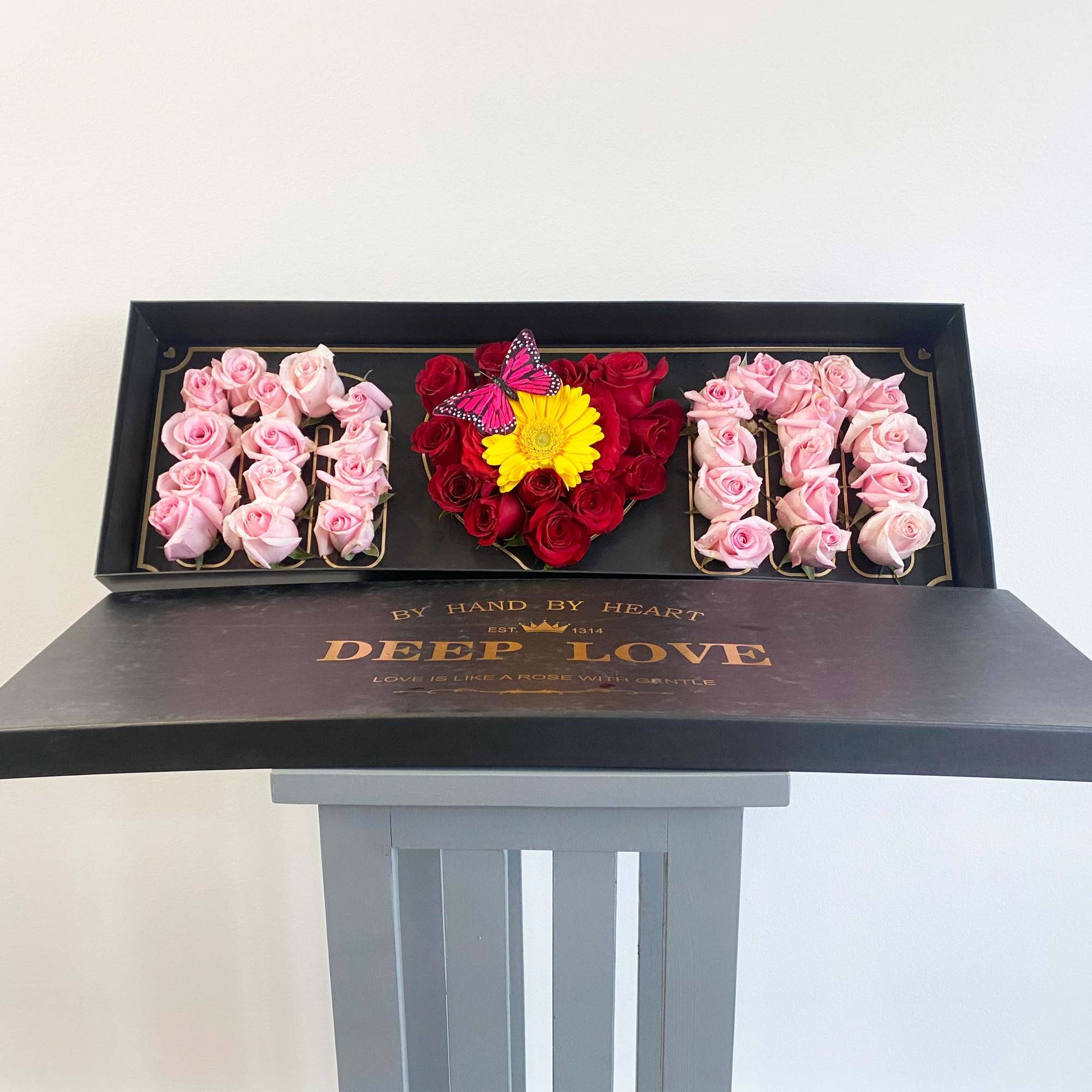 Heart-shaped rose box with pink and red roses and a yellow flower