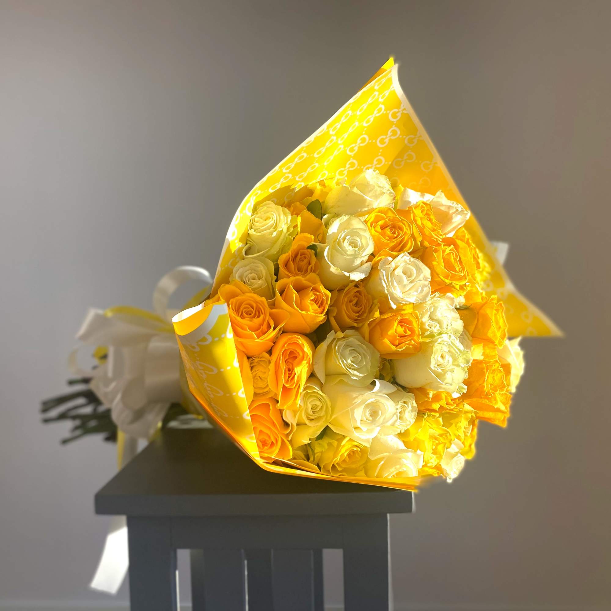 Bouquet of yellow and white roses wrapped in bright yellow paper
