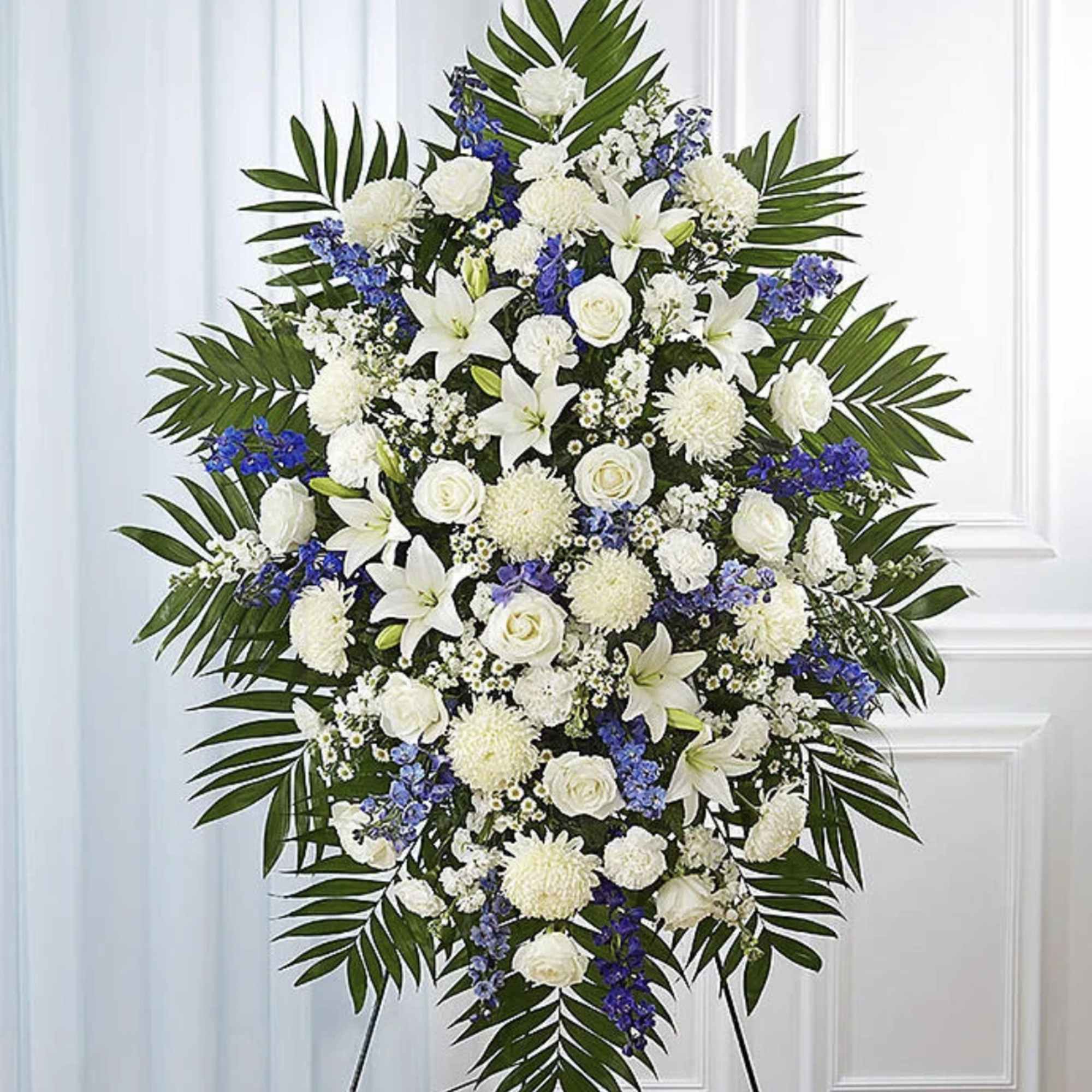 Standing funeral spray of white and blue flowers with palm fronds