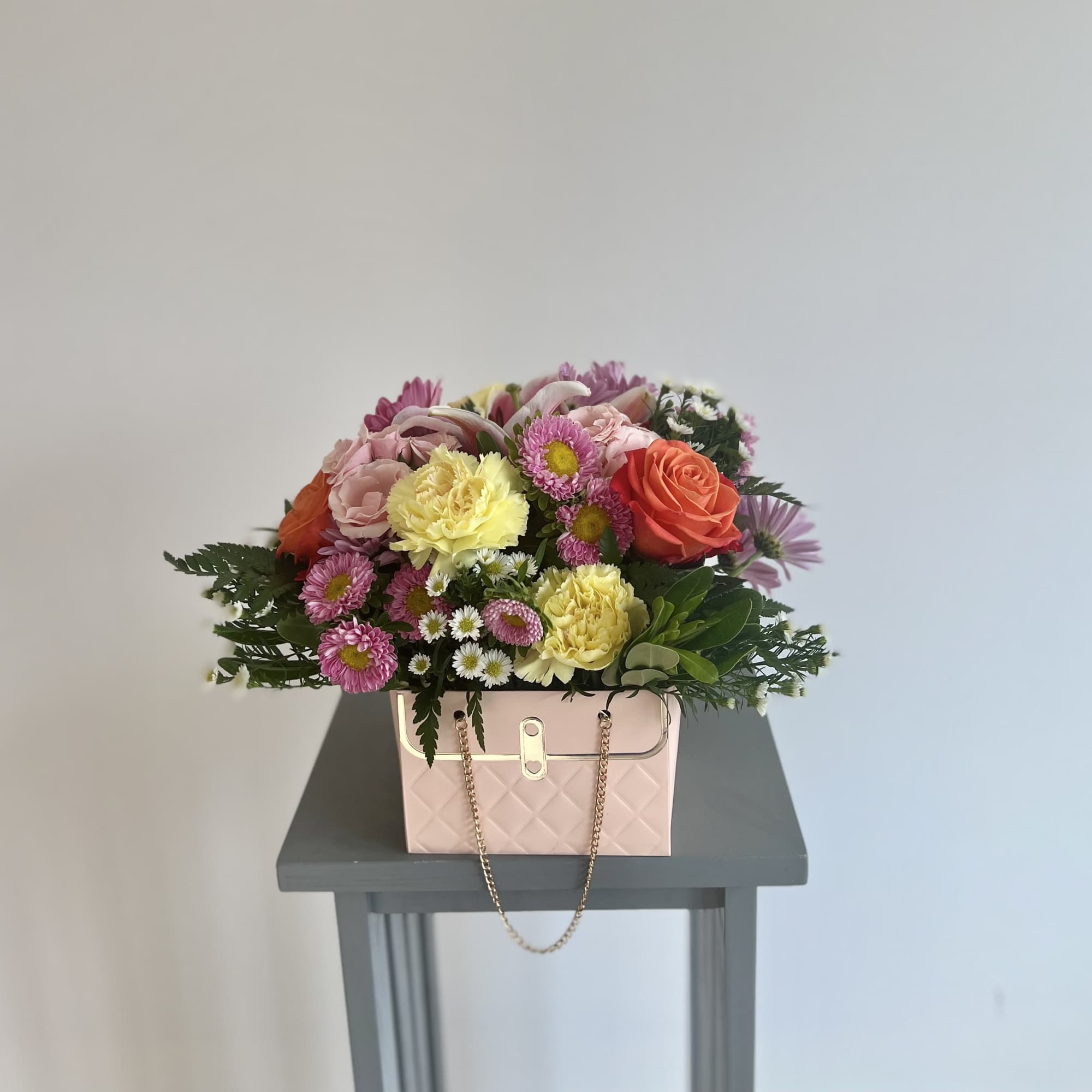 Mixed bouquet in a pink handbag-style box with a chain handle