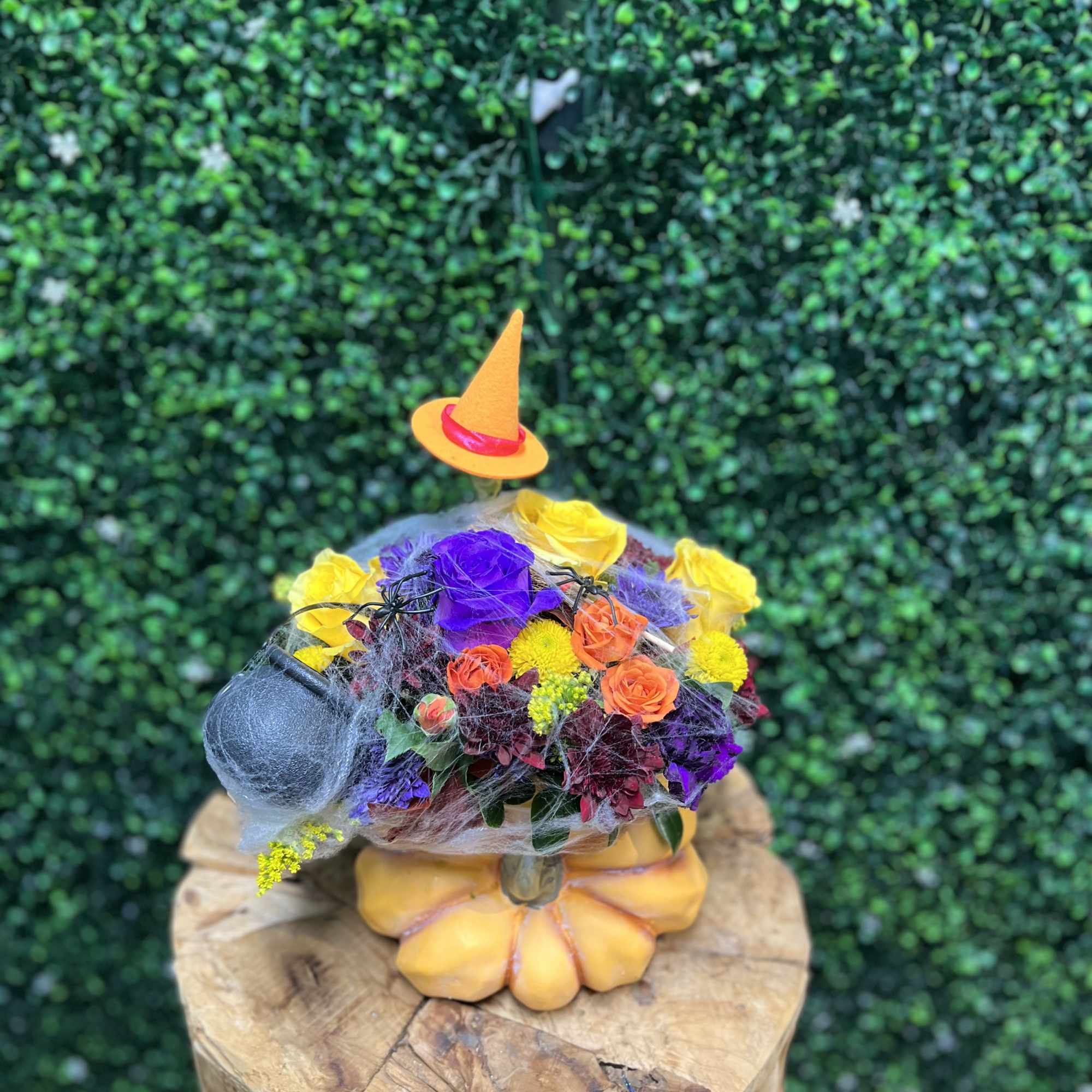 Colorful floral arrangement with a small witch hat on a pumpkin base