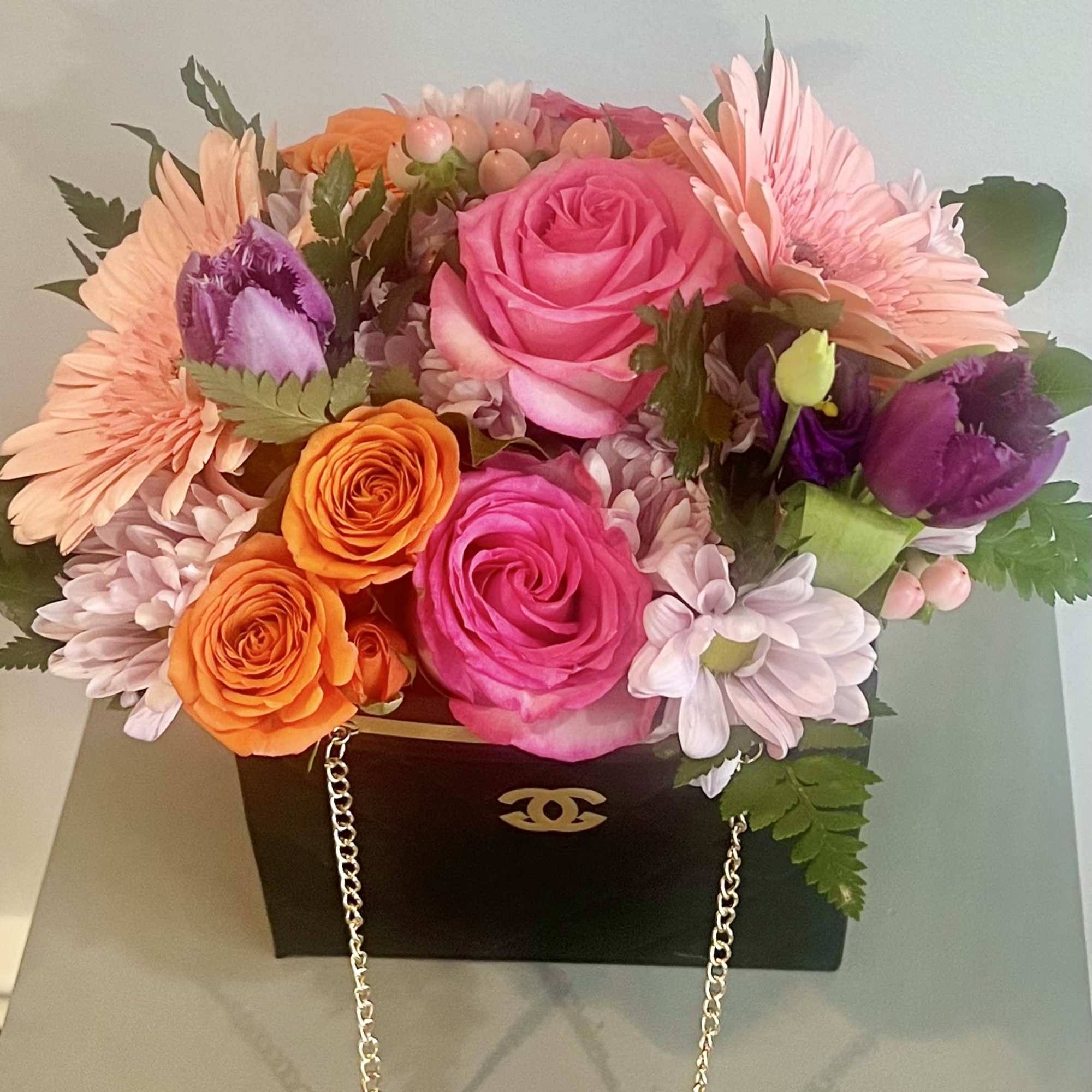 Colorful bouquet in a black handbag-style box with pink and orange flowers