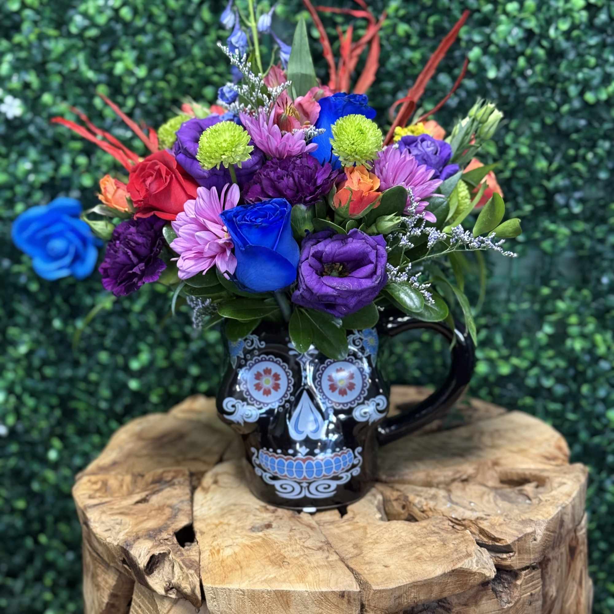 Colorful bouquet in a black skull mug on a wooden stand