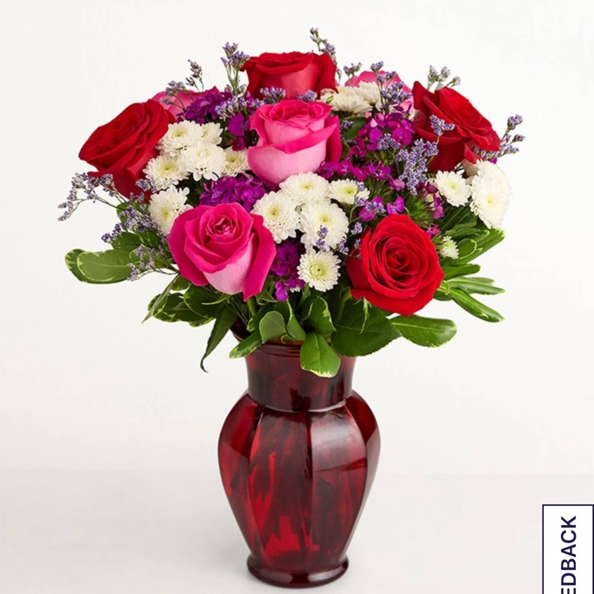 Bouquet of red and pink roses with white daisies in a red vase