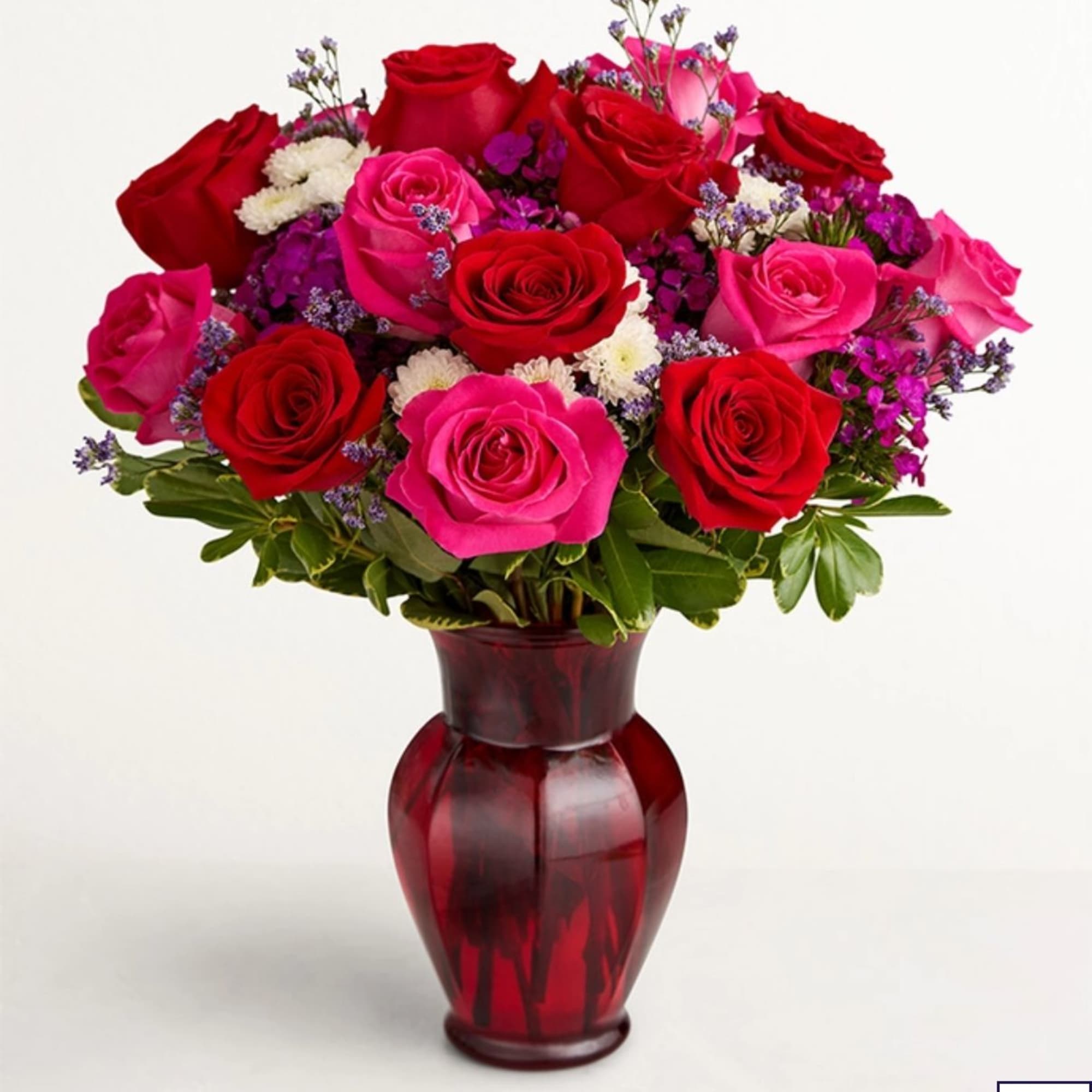 Red and pink roses arranged in a red glass vase