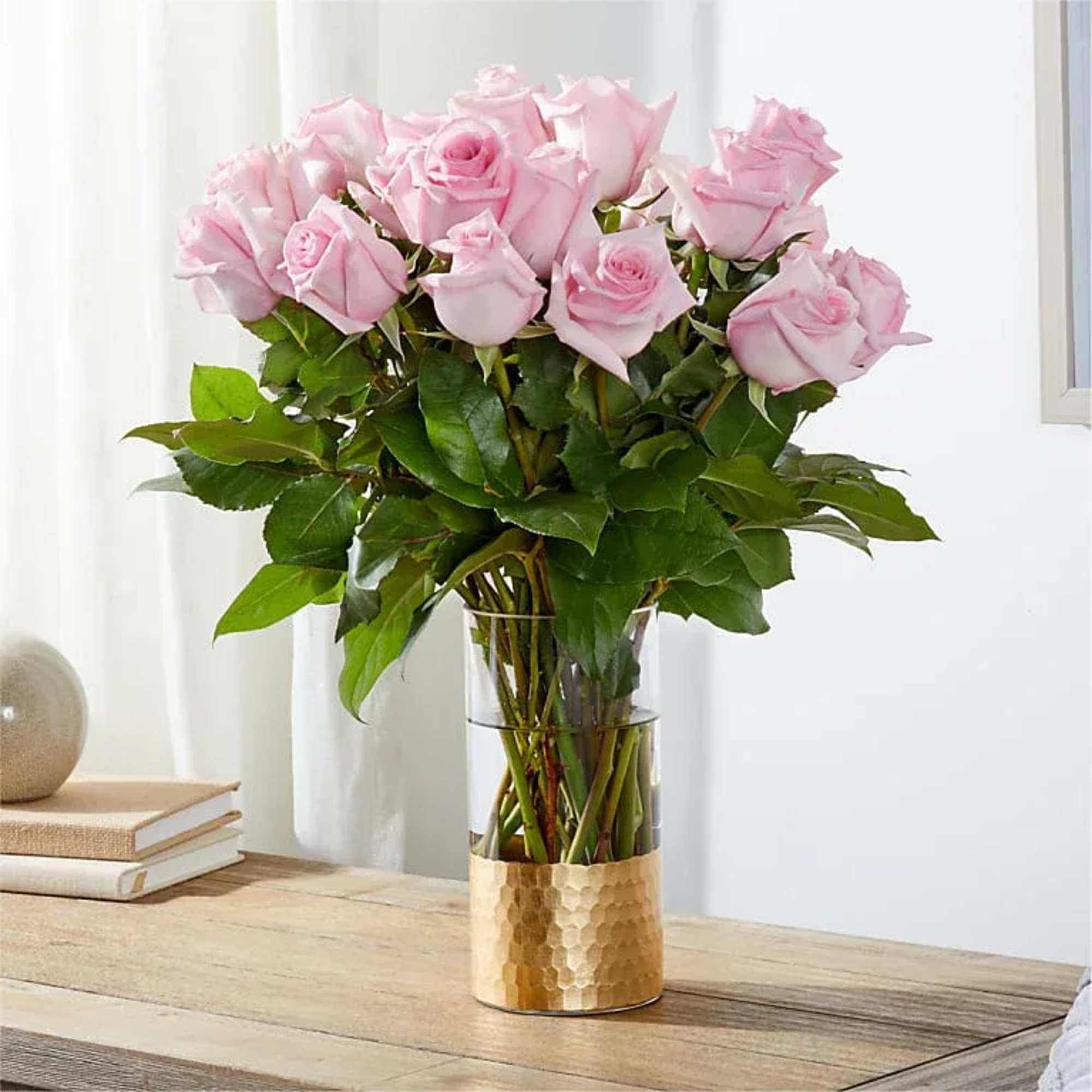 Pink roses in a clear vase with a gold base