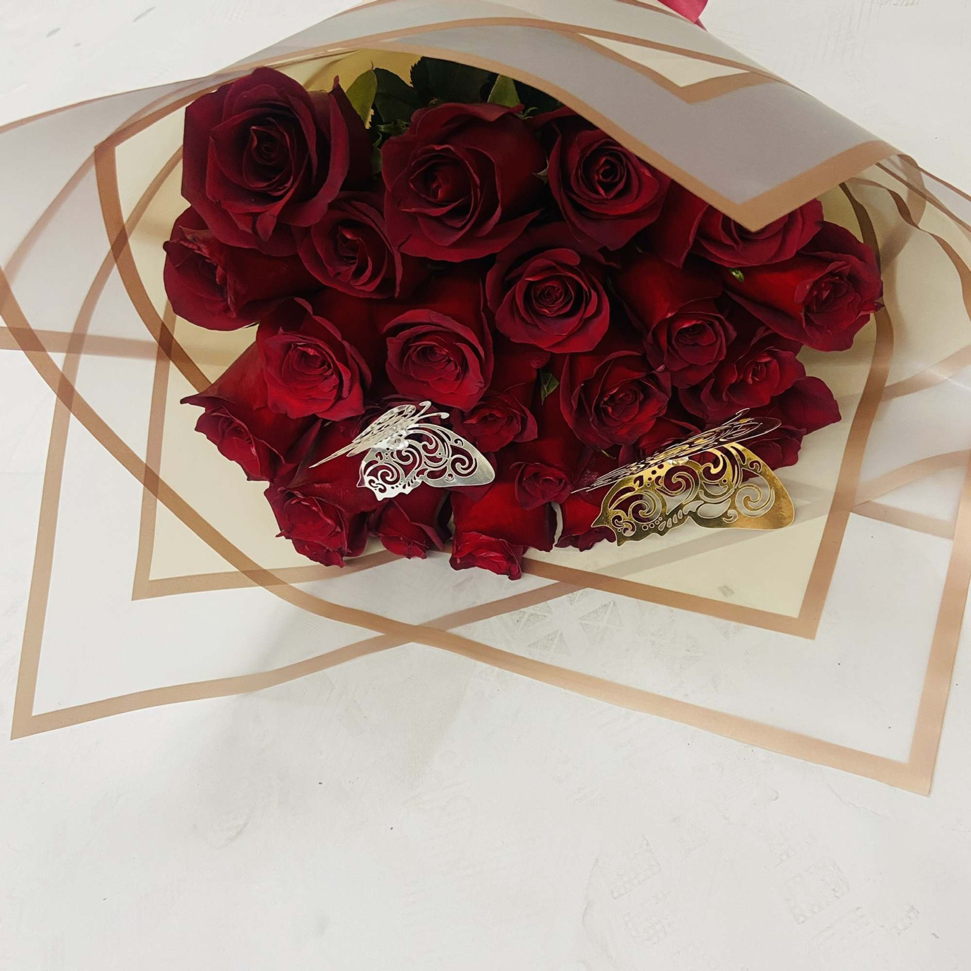 Bouquet of red roses wrapped in cream paper with a pink bow