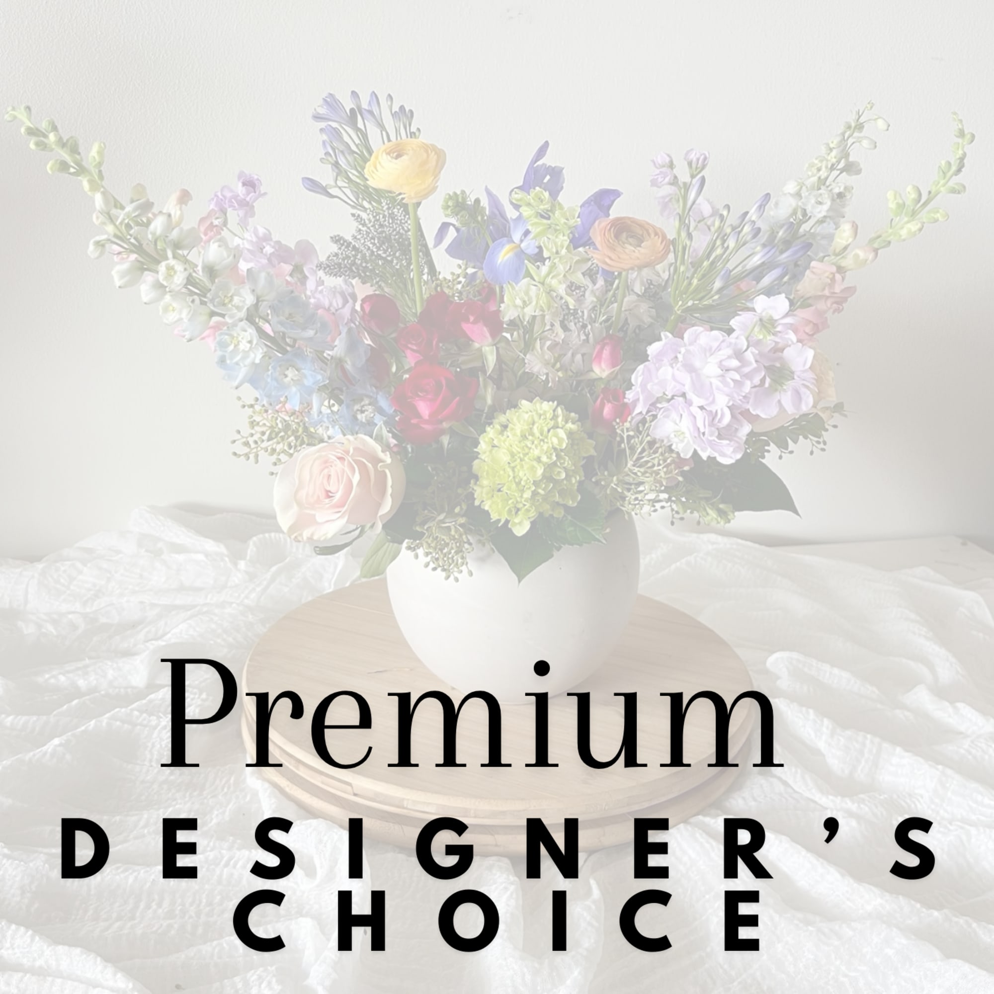 Colorful mixed flower arrangement in a white vase on a wooden tray with text reading Premium Designer's Choice.
