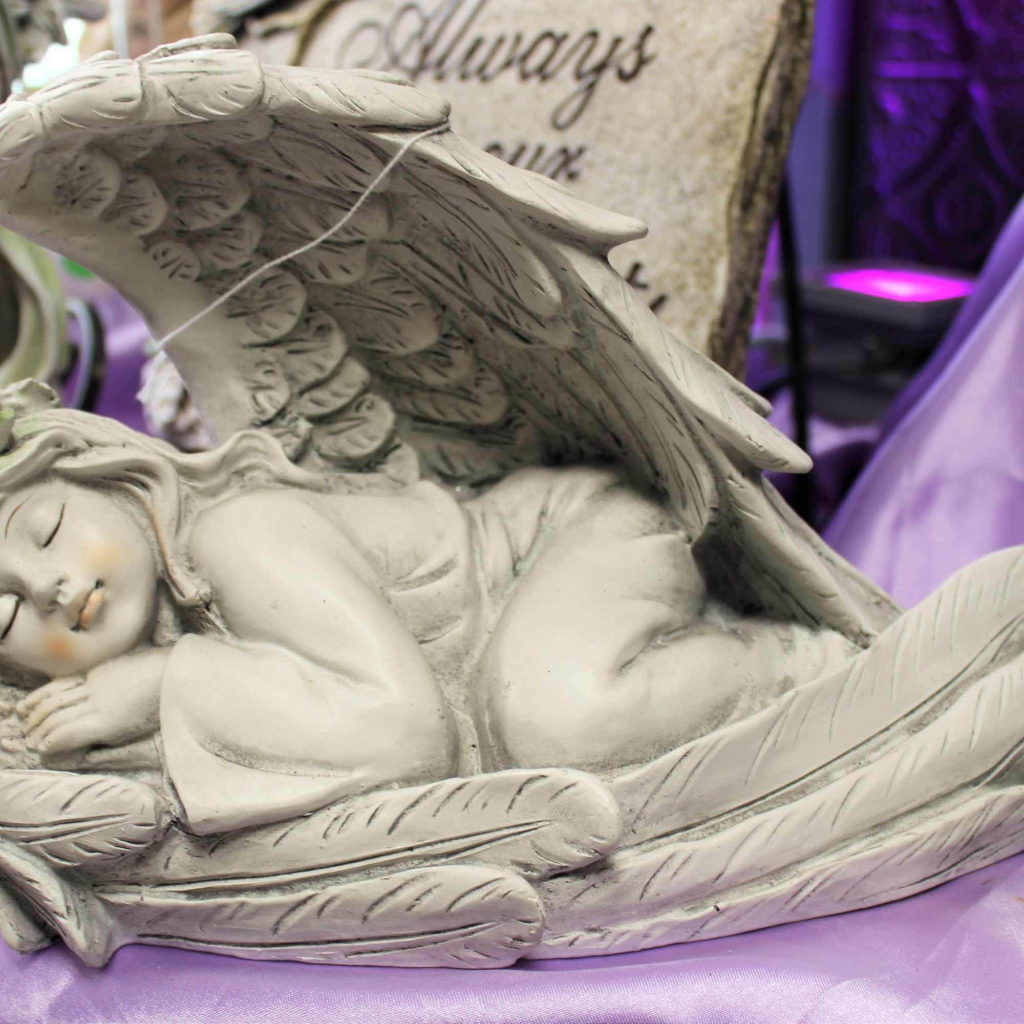 Sleeping angel figurine with wings on purple fabric