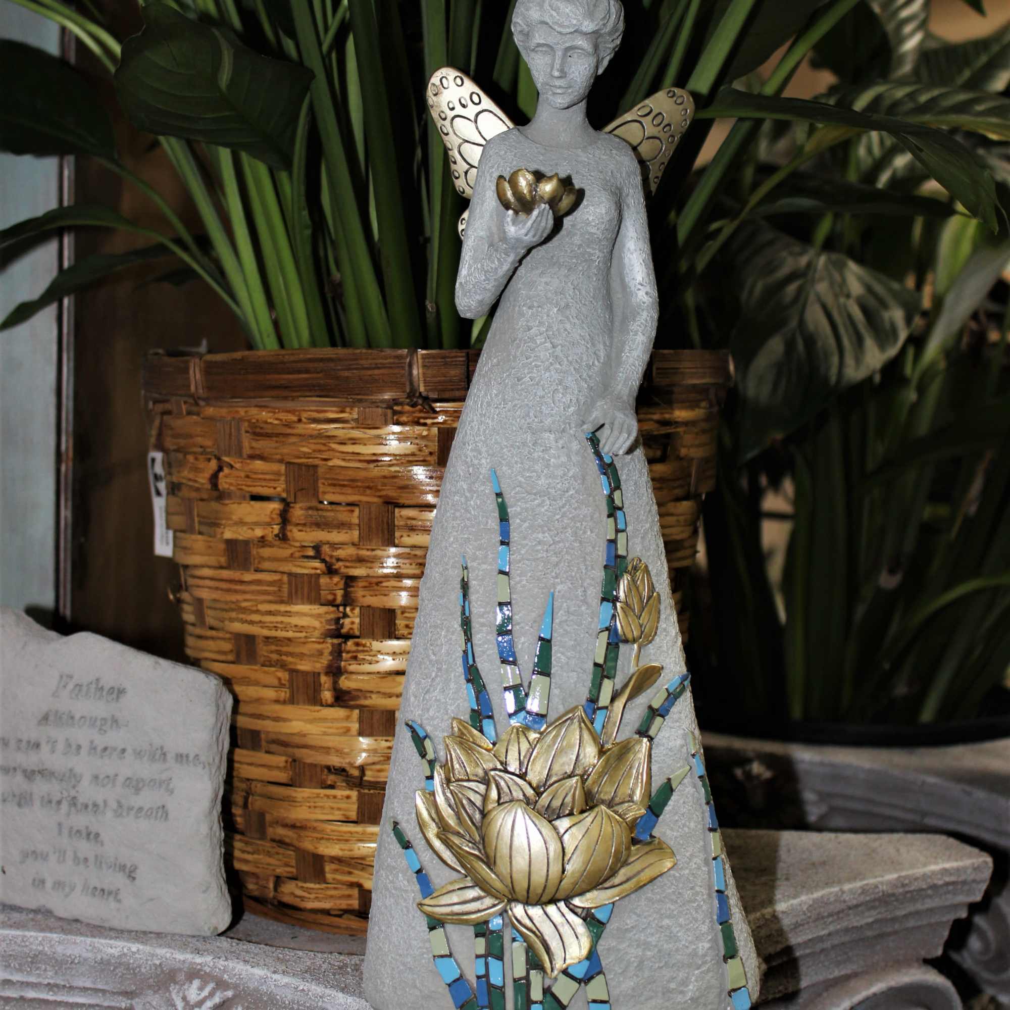 Decorative angel statue with mosaic flower detail beside a woven planter