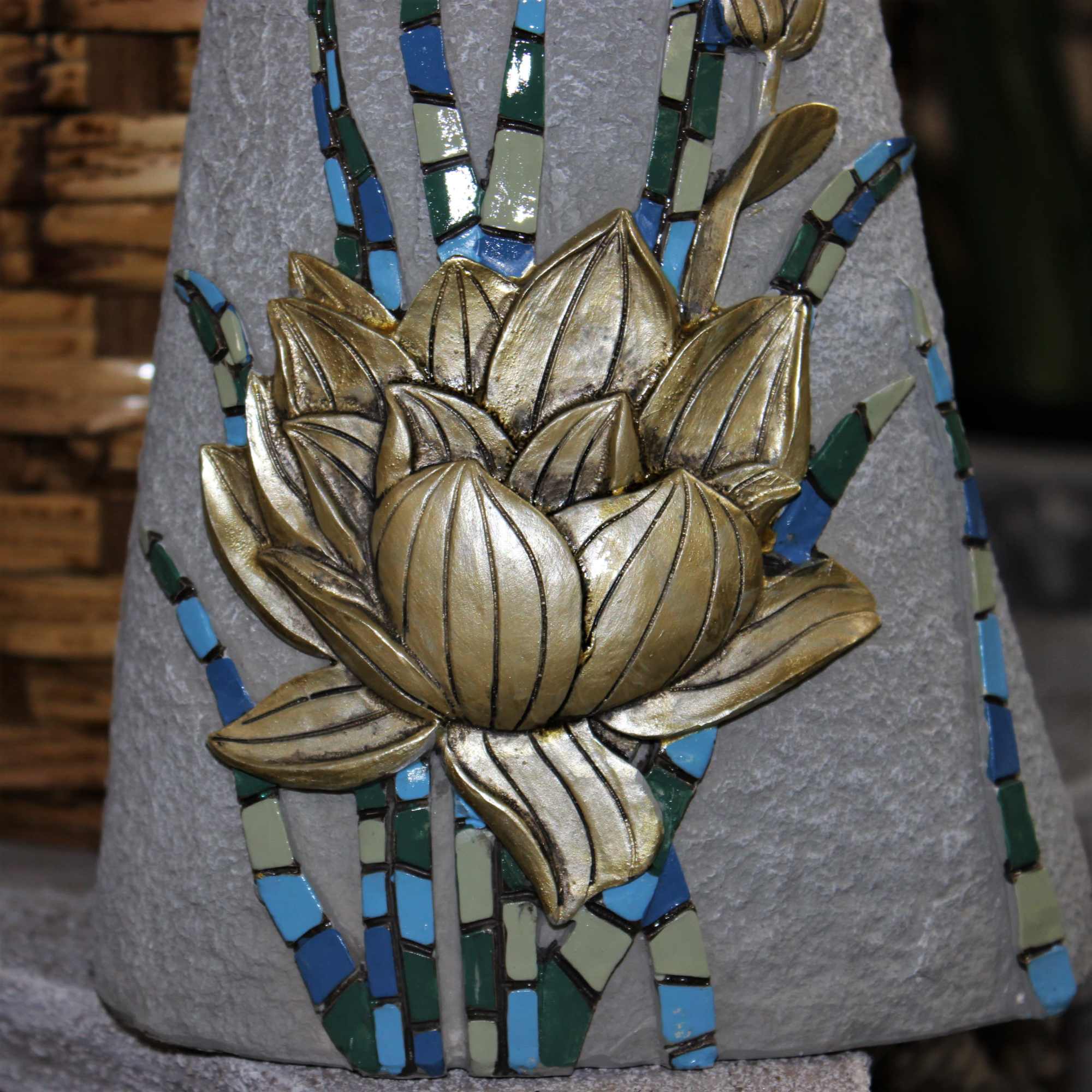 Gold lotus relief on a gray stone surface with blue and green mosaic accents