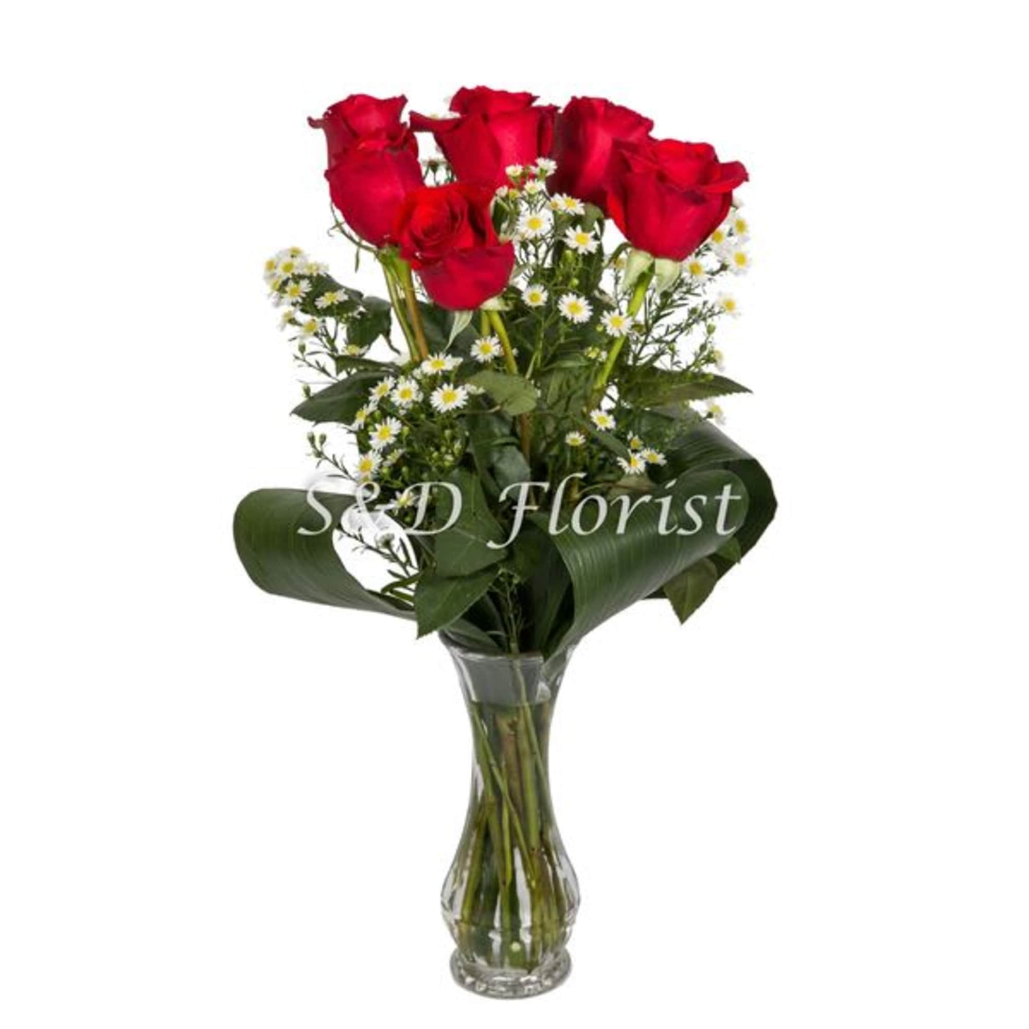 Red roses with small white daisies in a clear glass vase